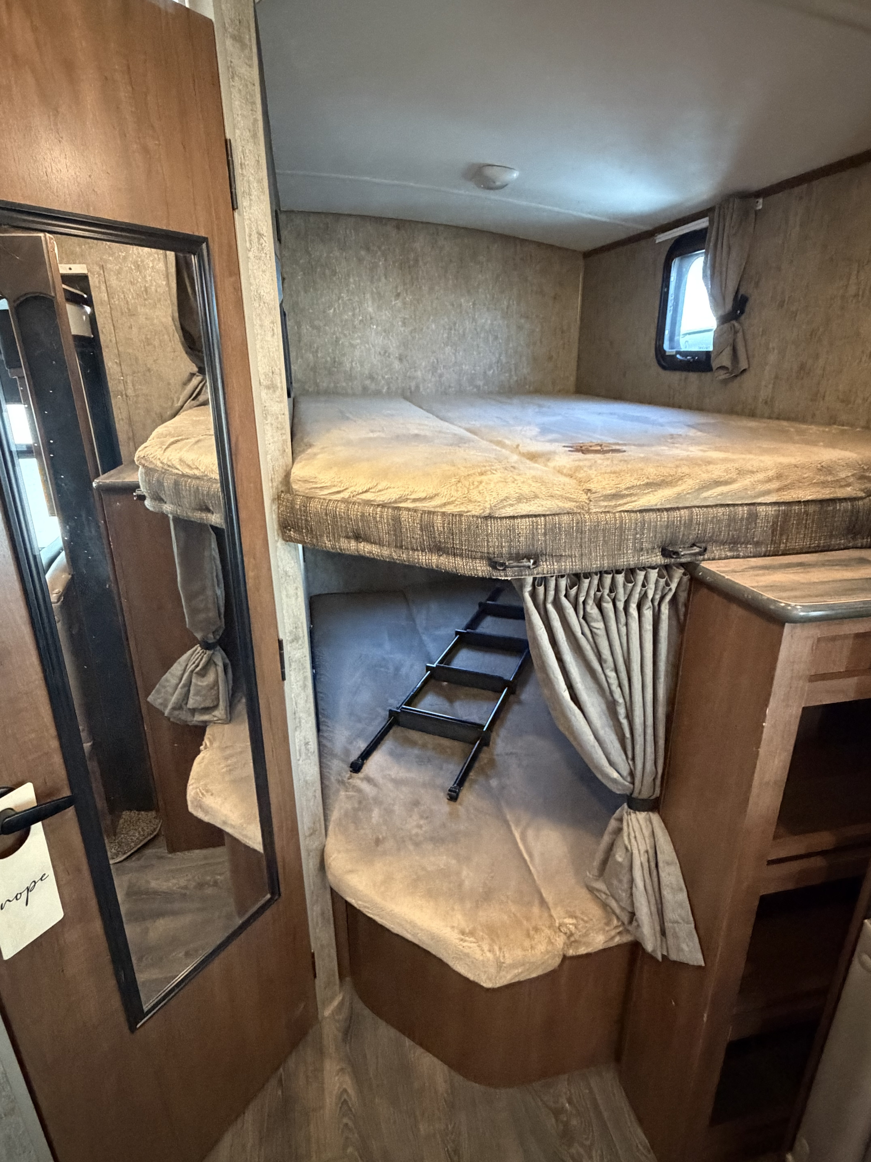 Inside an RV rental: a comfortable bunk bed area with an access ladder, window, curtains, and wood flooring.. Outdoors RV Mountain Trax Backcountry 2022