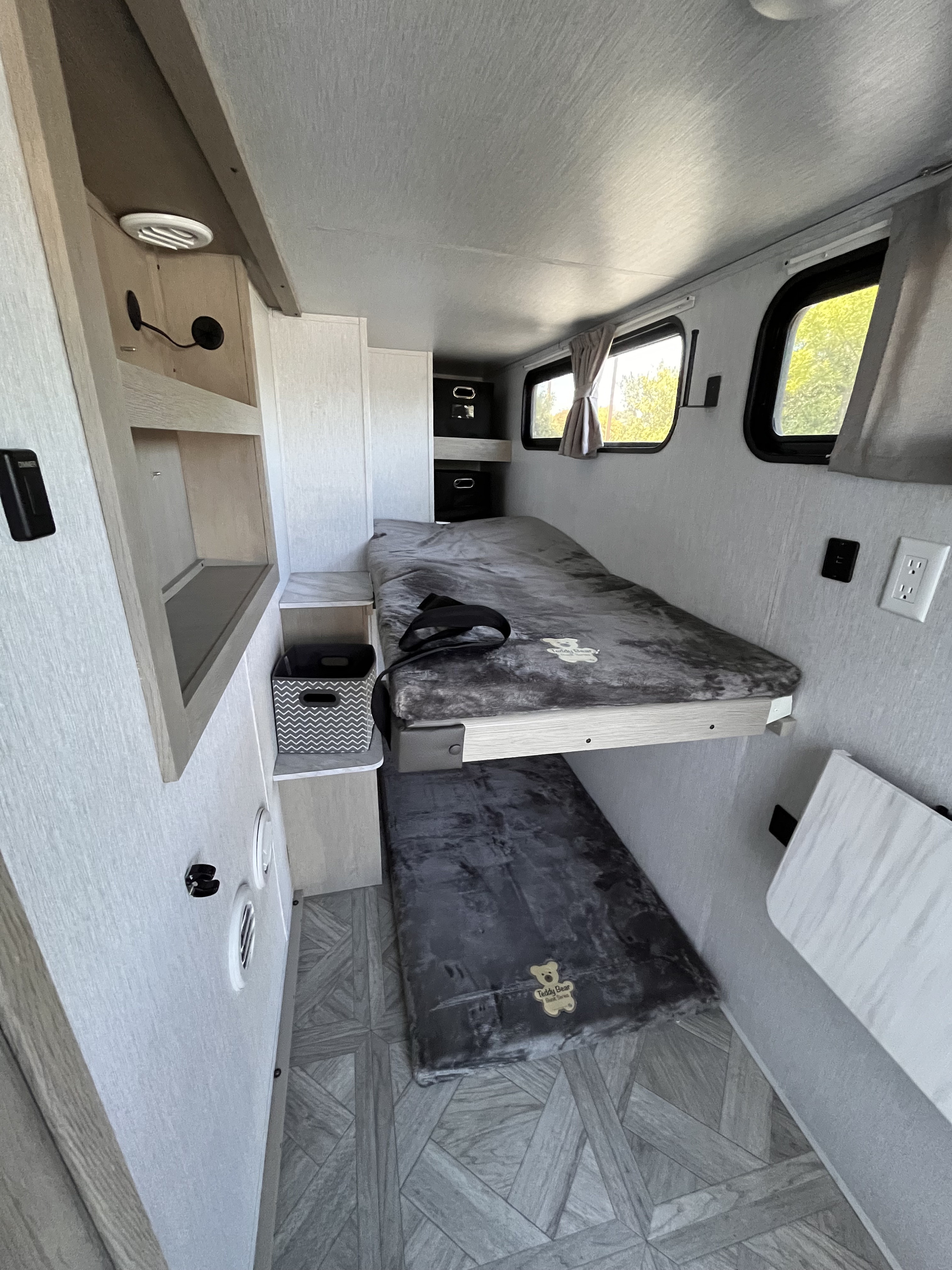 Cozy RV rental bunk bed sleeping area with shelves, windows, and geometric floor. Ideal for compact travel.. Forest River Salem 2024