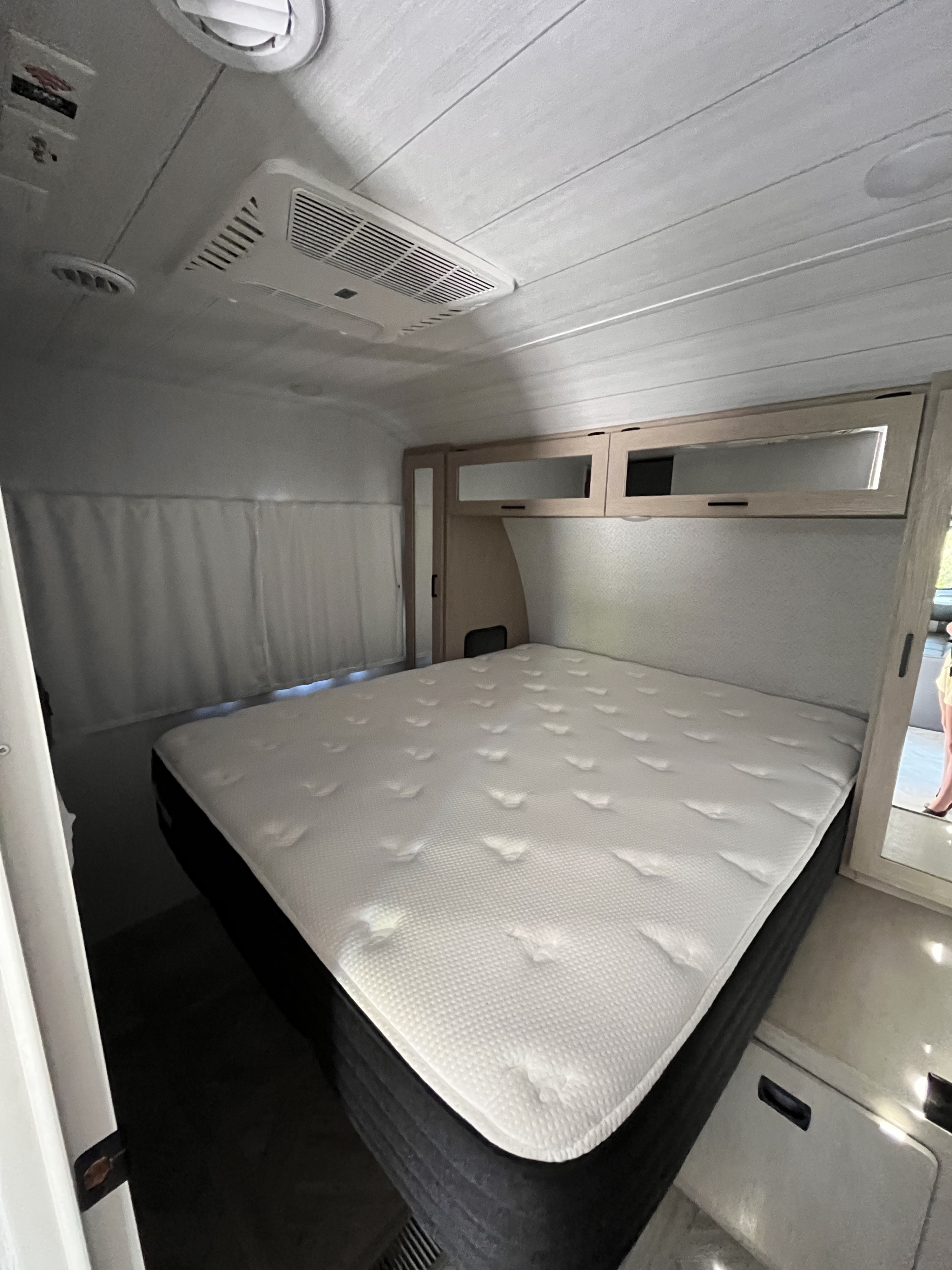 Clean and inviting RV rental bedroom with a large, plush mattress, overhead cabinets, and AC, ready for your adventures.. Forest River Salem 2024