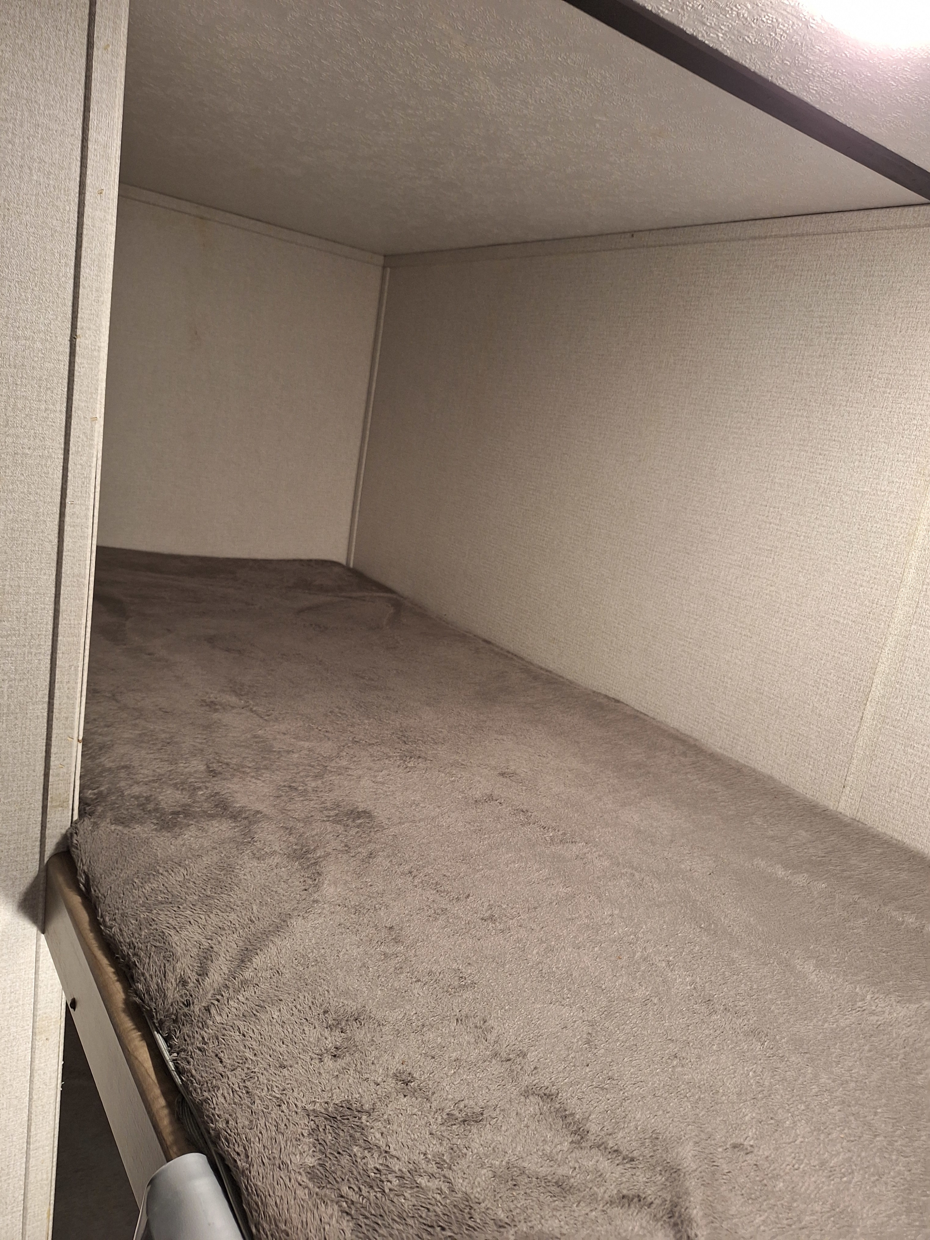 Inside an RV rental: a cozy, empty bunk bed with a soft gray blanket, ready for camping and travel adventures.. Keystone RV Hideout LHS Mini 2020