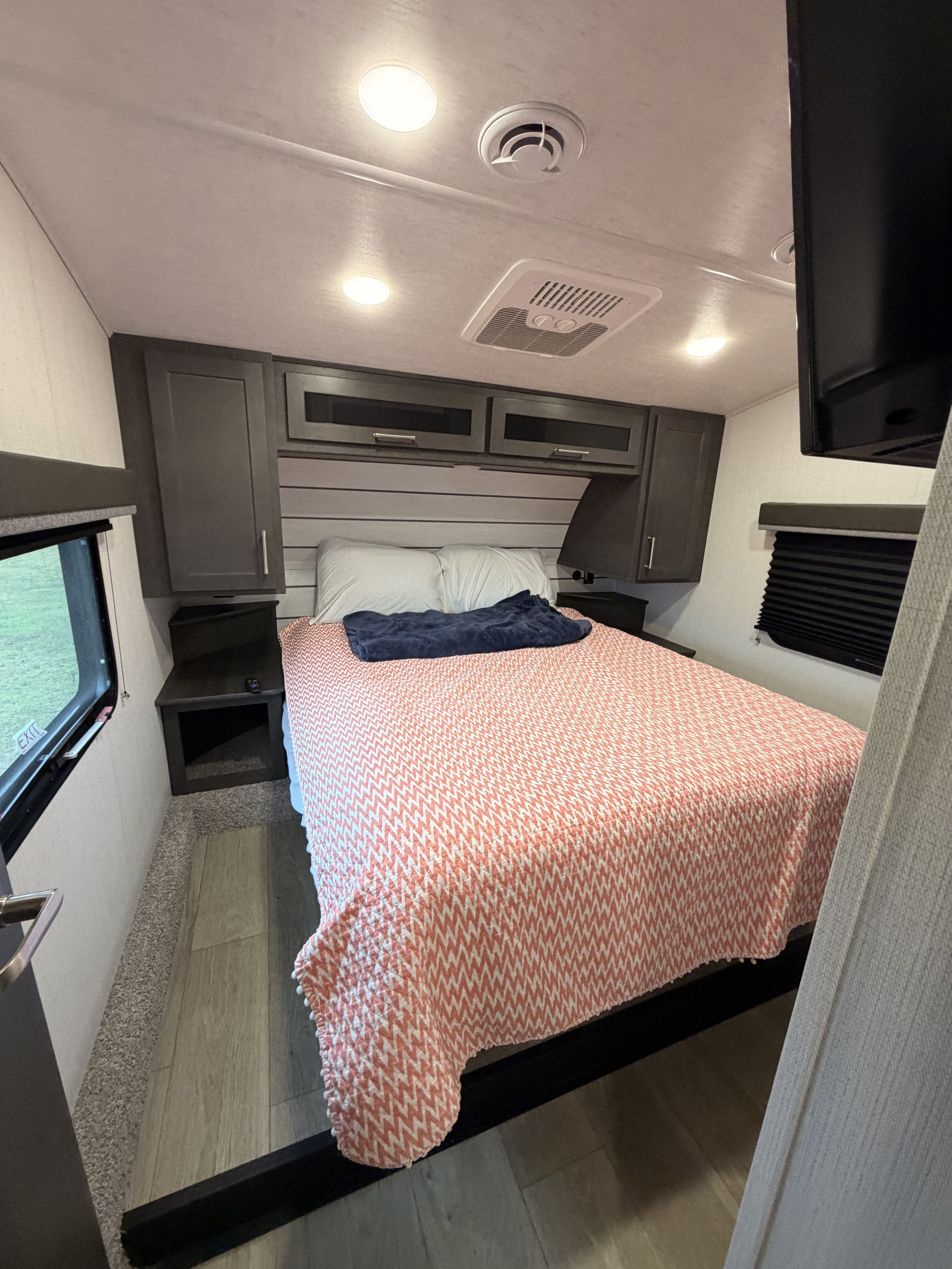 Step into comfort in this modern rv rental bedroom featuring a queen bed, ample storage, and natural light from the windows.. Keystone RV Cougar Sport 2025