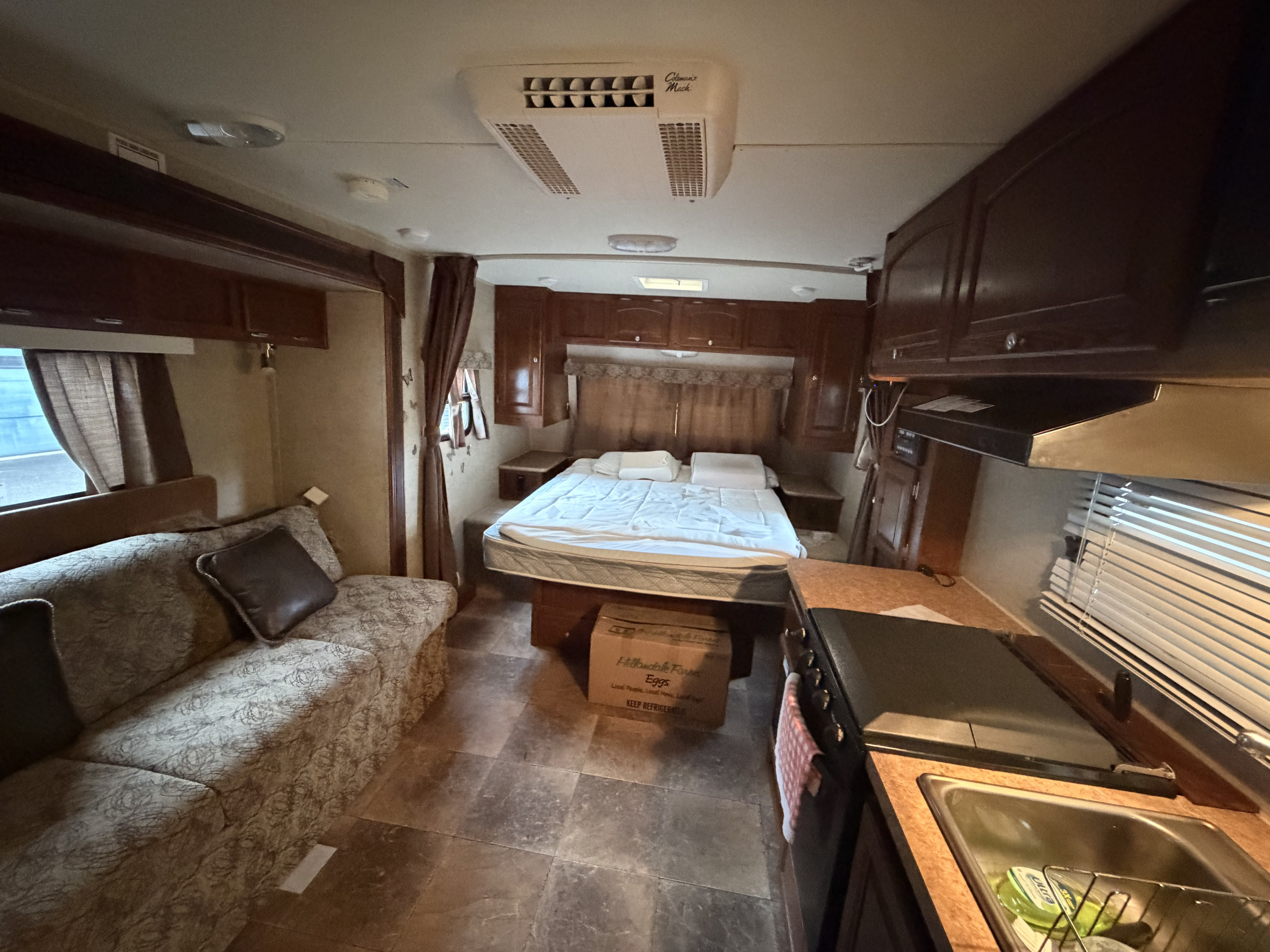 RV rental interior featuring a cozy bed, compact kitchen with sink/stove, and a comfortable living area sofa, perfect for trips.. Forest River Rockwood Mini Lite 2013