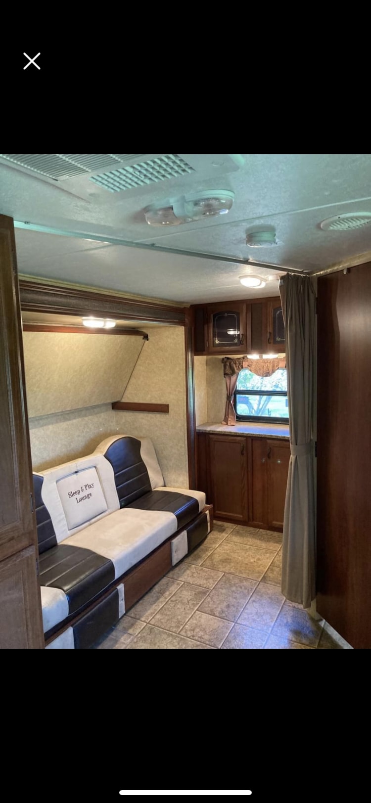 Cozy interior of this RV rental, featuring a convertible couch, wood cabinetry, and tile floor.. Forest River Tracer Executive 2010