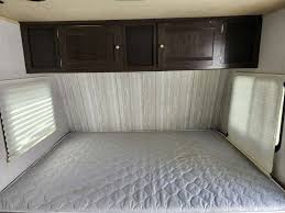 RV rental sleeping area featuring a mattress, overhead cabinets, and blinds for privacy.. Heartland RVs Pioneer 2018