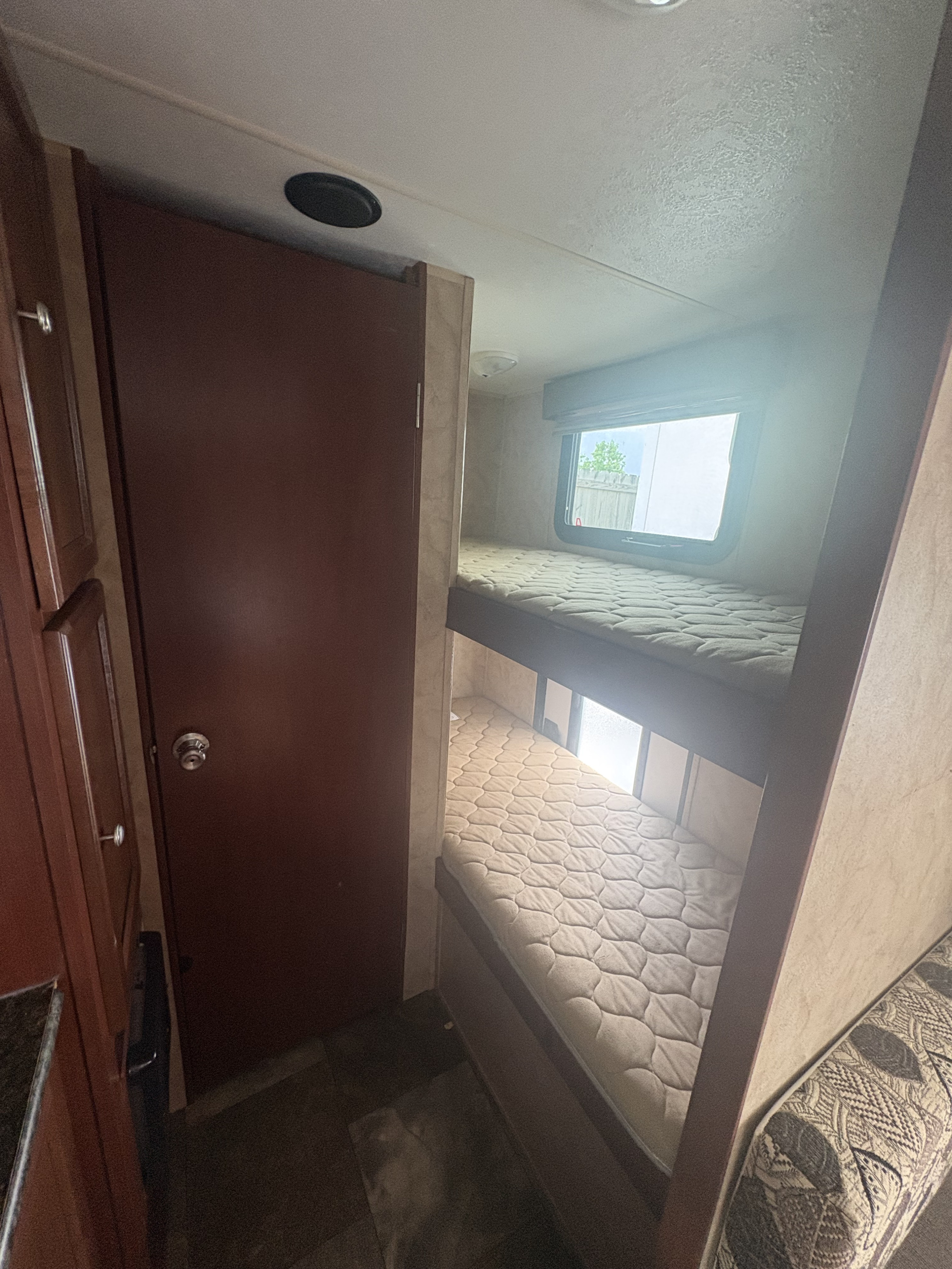 Compact RV rental interior featuring cozy bunk beds and a nearby door, ideal for a family getaway.. Coachmen Clipper 17BH 2015