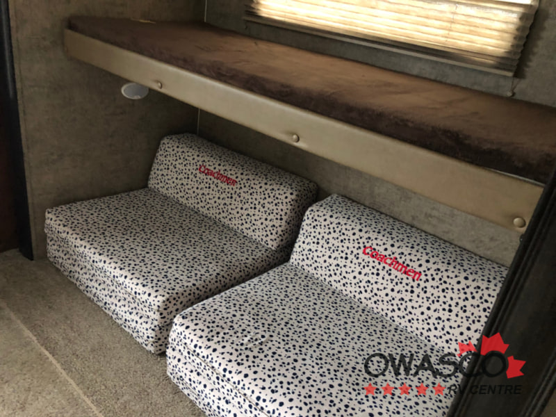 RV rental comfort: Bunk bed with flexible seating below, featuring patterned Coachmen cushions, ideal for families.. Coachmen Freedom Express 312BHDS Travel Trailer 2017