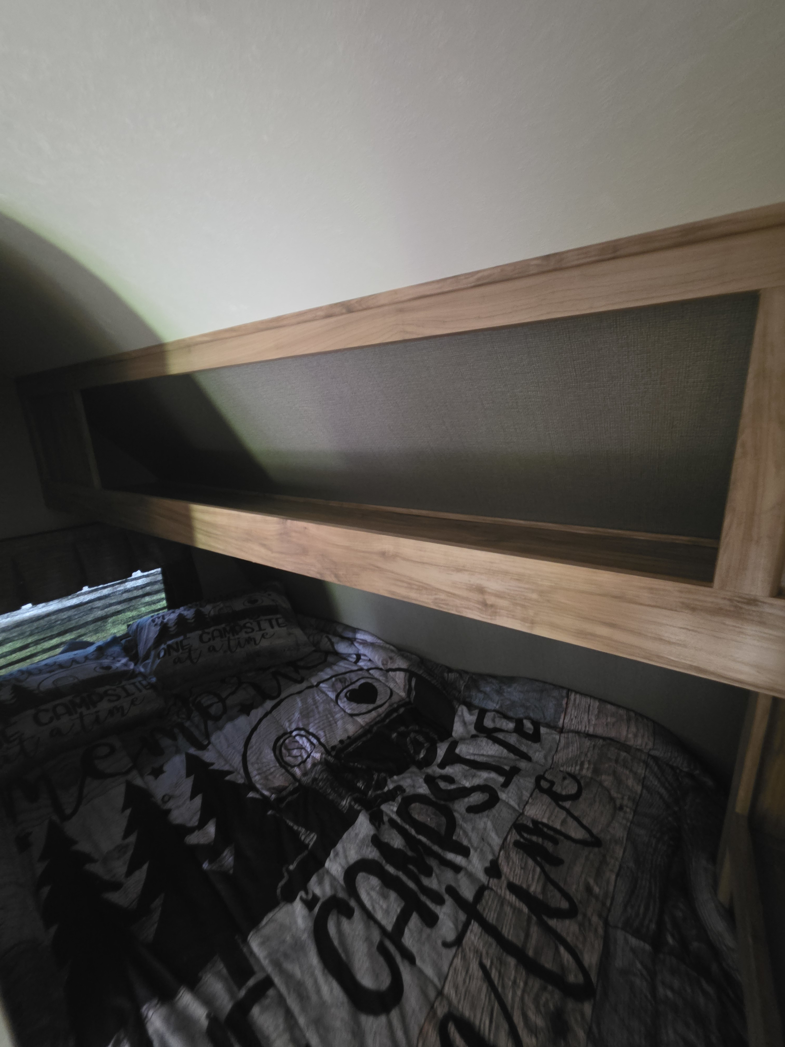 Experience comfort in your RV rental with this cozy bunk bed, "ONE CAMPSITE" bedding, and convenient overhead storage.. Coachmen Blast 2018