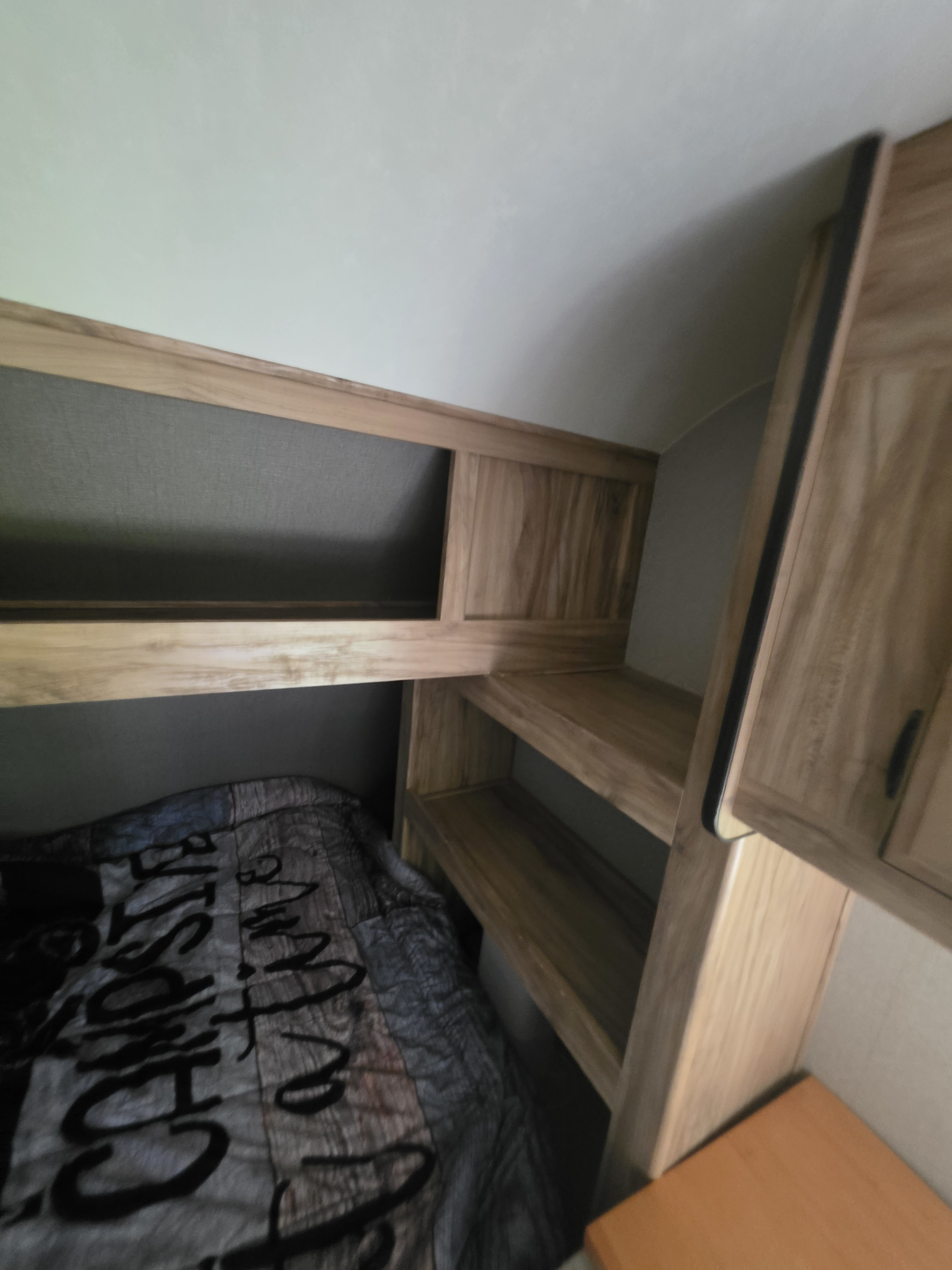 Cozy RV rental sleeping area with bunk beds, wooden shelves, and storage cabinet, ideal for families on the go.. Coachmen Blast 2018
