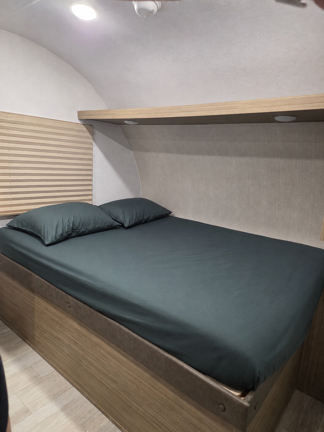 Cozy rv rental bedroom with dark sheets, a wooden shelf with lights, and window blinds for comfort.. Forest River Salem 2026