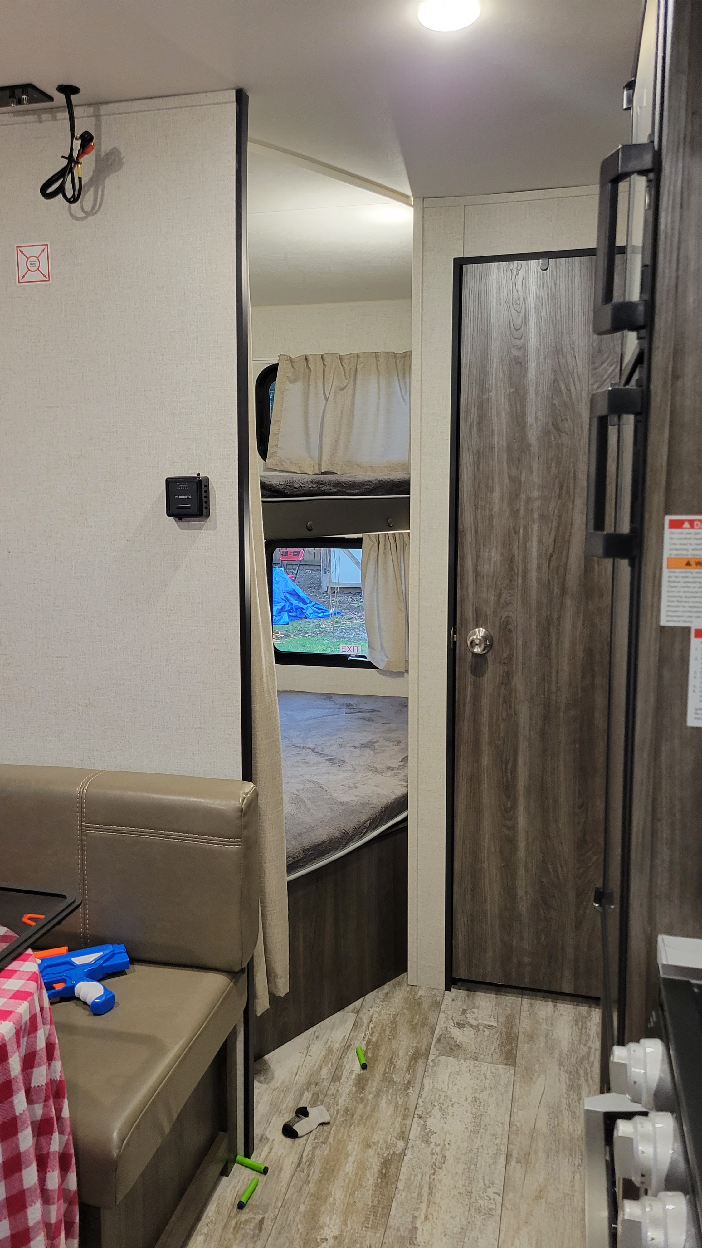 Inside an RV rental featuring bunk beds, a dining booth, thermostat, and wood-look flooring. Ready for your next adventure!. Highland Ridge RV Open Range 2020