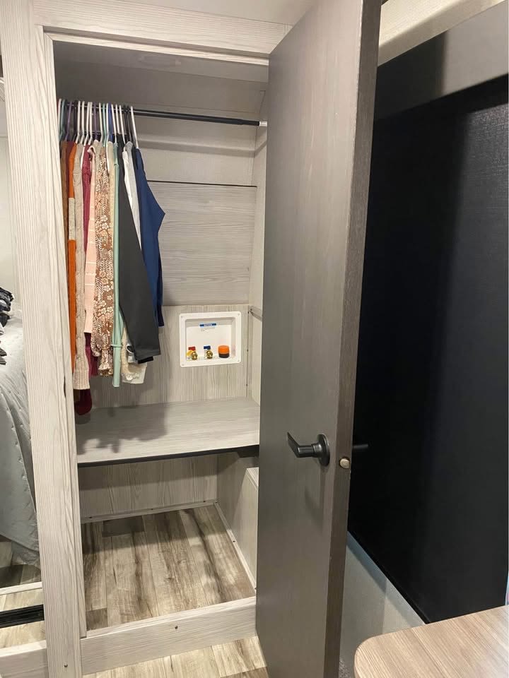 RV rental closet, ready for laundry with a washer/dryer hookup, clothing rod, and shelf. Light wood interior offers practical storage.. Keystone RV Montana High Country 2024