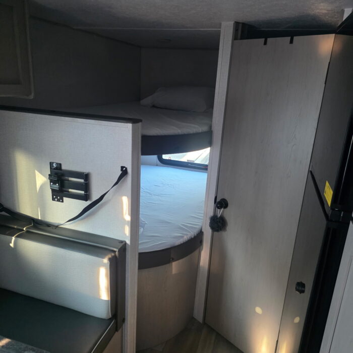RV rental interior featuring comfortable bunk beds, a cozy dinette area, and a compact refrigerator, perfect for travel.. Clipper 5K 2024