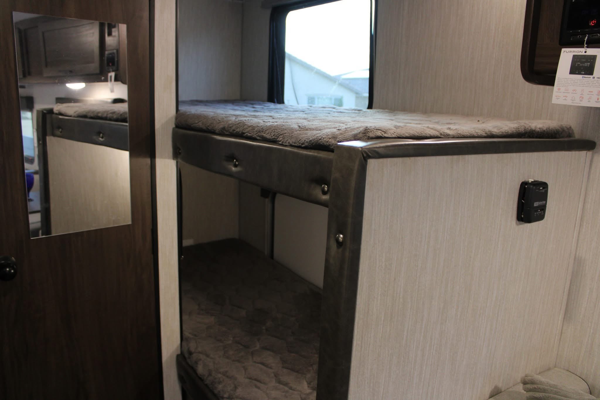 Cozy bunk beds with plush bedding inside a modern RV rental, featuring a window view and integrated controls.. Forest River Cherokee Wolf Pup 2020