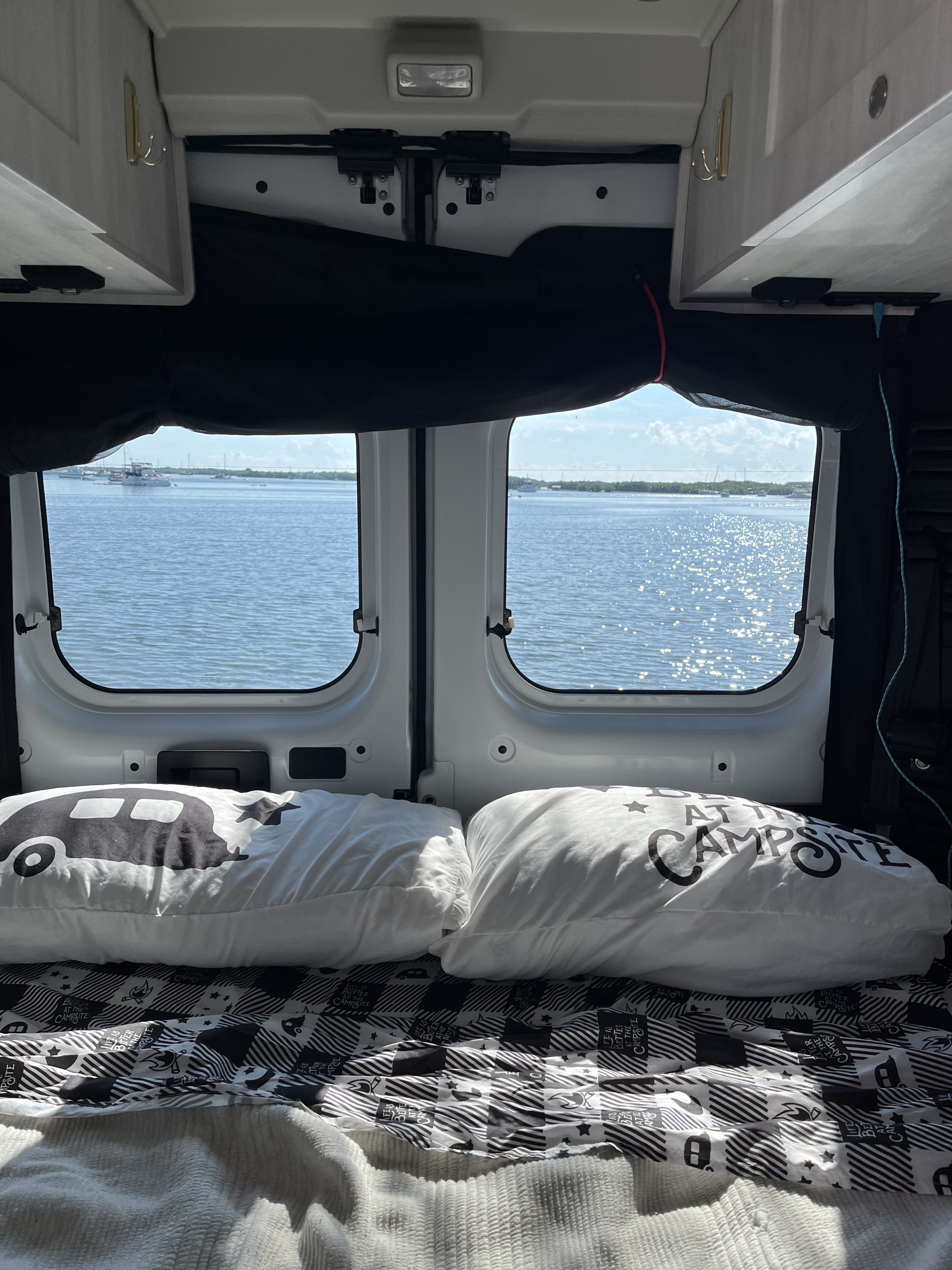 Enjoying the serene waterfront view from inside a cozy RV rental camper van, perfect for a relaxing travel & camping getaway.. Roadtrek Roadtrek Class B 2023