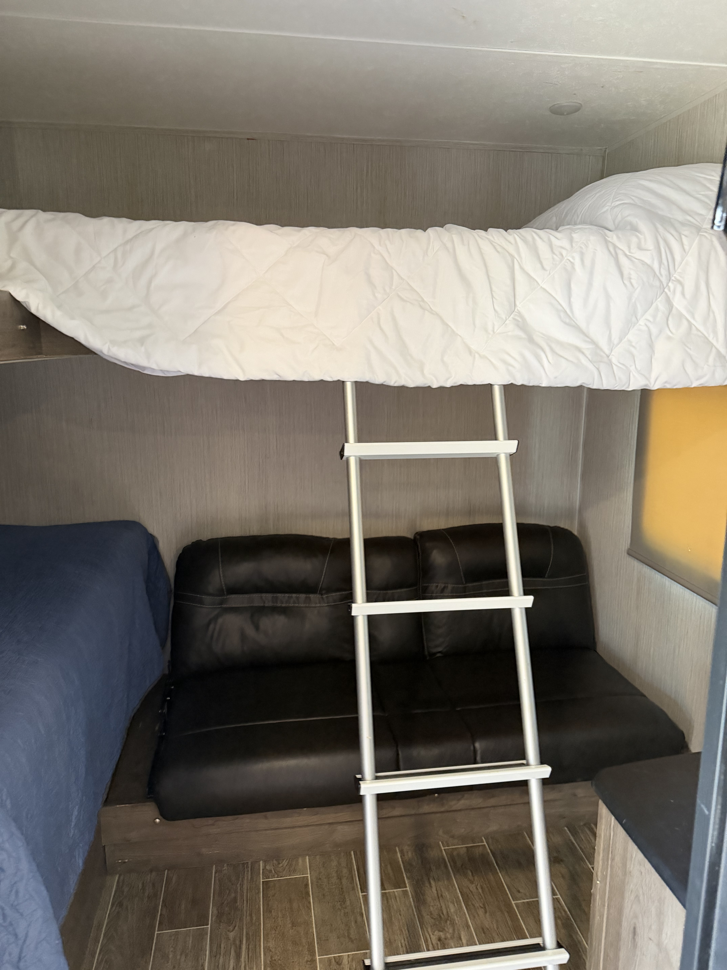 RV rental bedroom with bunk bed, ladder, black sofa bed, and another sleeping area for guests.. Forest River Palomino Puma 2021