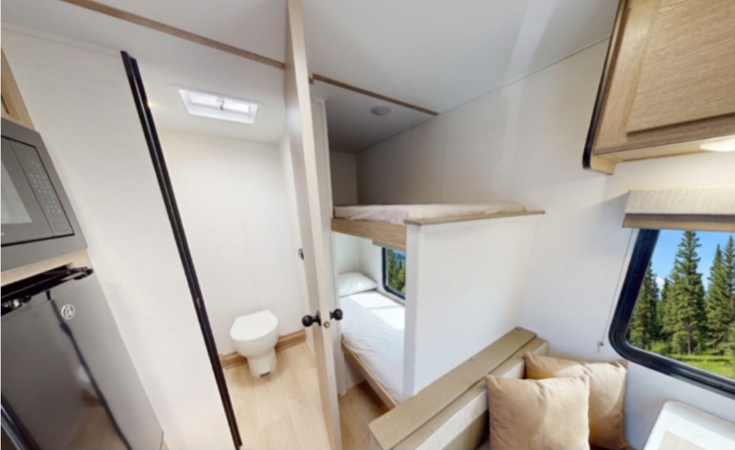 Inside a modern RV rental: microwave, fridge, toilet, comfy bunk beds, and scenic window views for your trip.. Grand River 17BHG 2026
