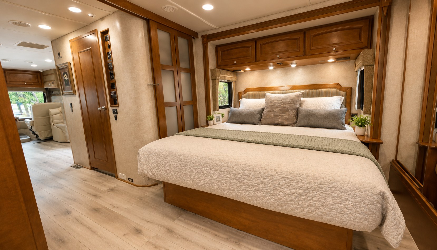 Comfortable RV rental bedroom featuring a queen bed, warm wood cabinets, and modern flooring, offering a cozy retreat.. Winnebago Adventurer 2012