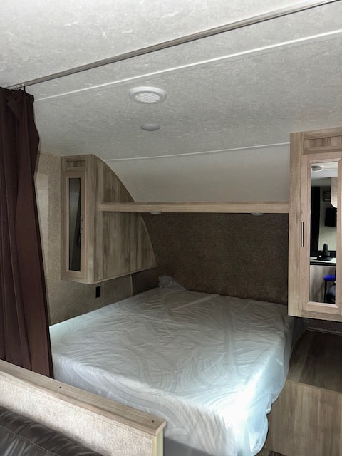 RV rental bedroom interior: queen bed with fresh cover, wood cabinets, and mirrored wardrobe, ready for use.. Coachmen SBX 261BH 2020