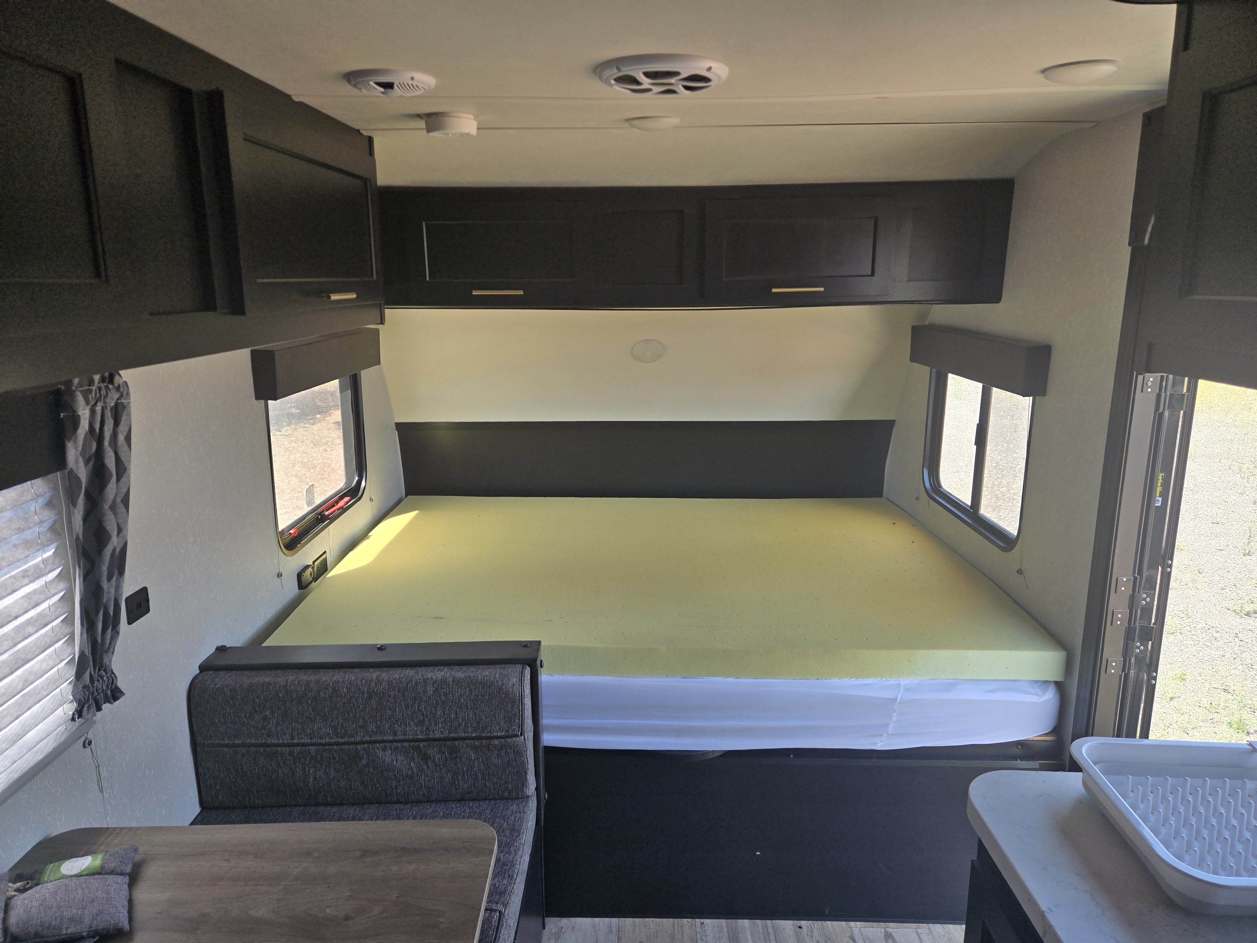 Bright rv rental interior features a bed with foam topper, dark cabinets, dinette, and large windows.. Forest River Cherokee Wolf Pup 2022