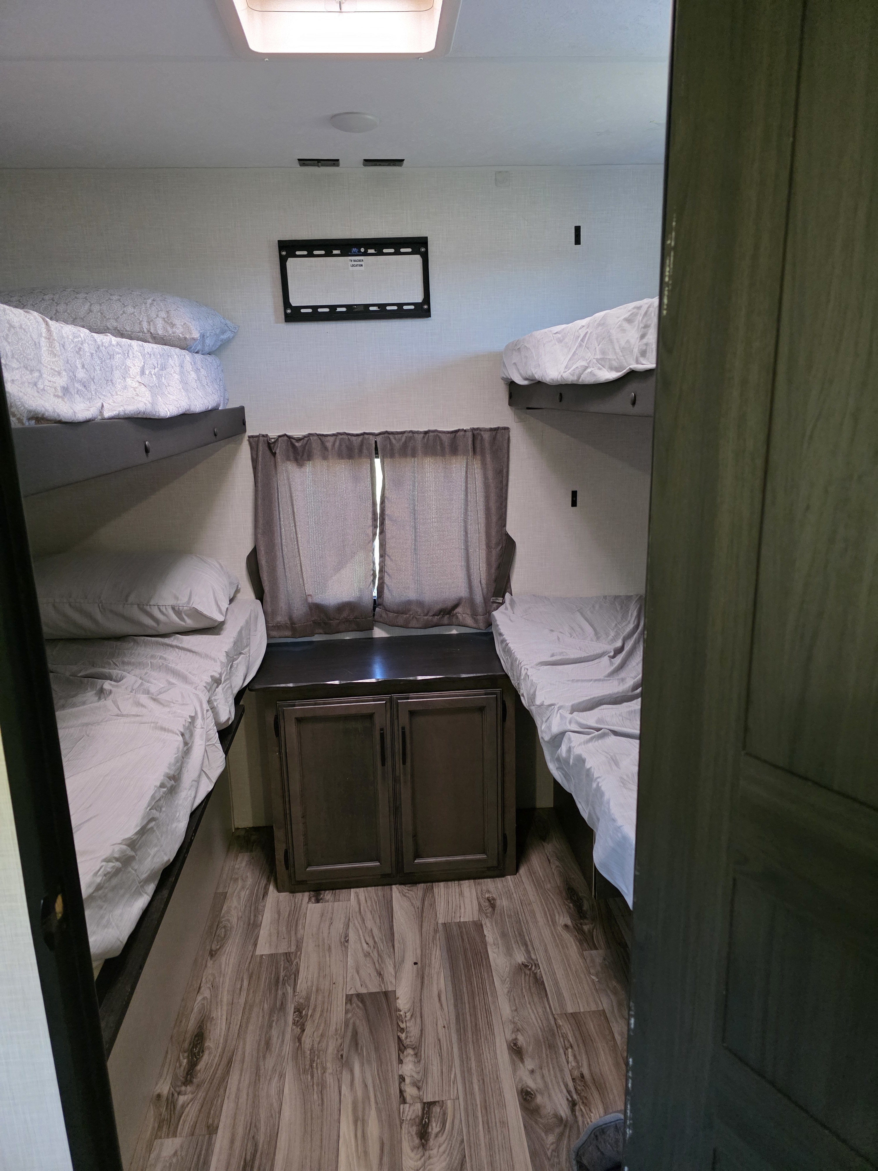 RV rental bunk room featuring four beds, a central cabinet, and TV mount for comfortable travel.. Sporttrek Touring Edition 2024