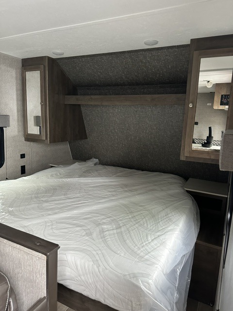 Cozy RV rental bedroom featuring a mattress in plastic, overhead storage, and built-in nightstands for comfort.. Dutchmen Coleman Lantern LT 2020