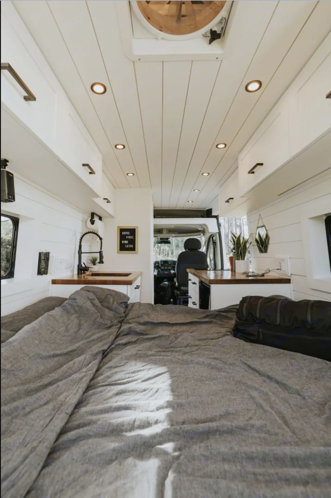 Cozy rv rental interior with bed, kitchen, and workspace. Perfect for van life adventures, clean and modern.. Ram ProMaster 2500 2024