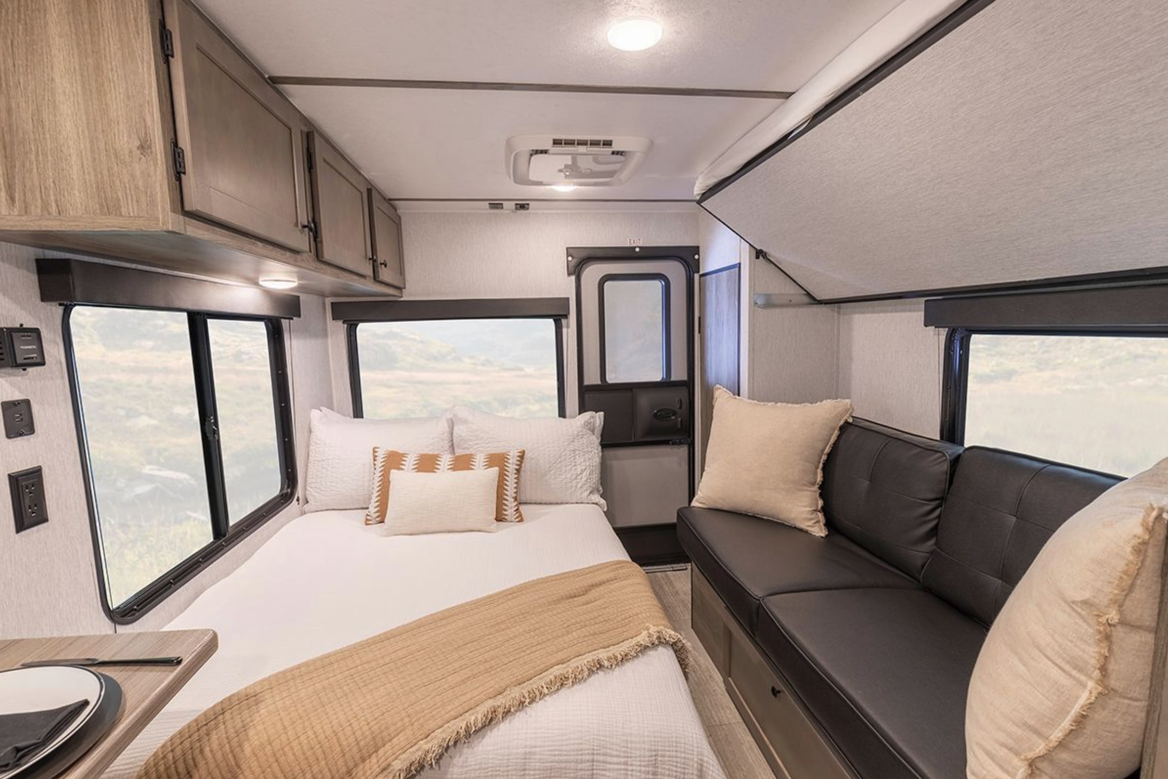Explore this modern RV rental interior with a comfy bed, sofa, windows with views, and practical overhead storage.. Wayfinder Go Lite Cloudbreaker 2026