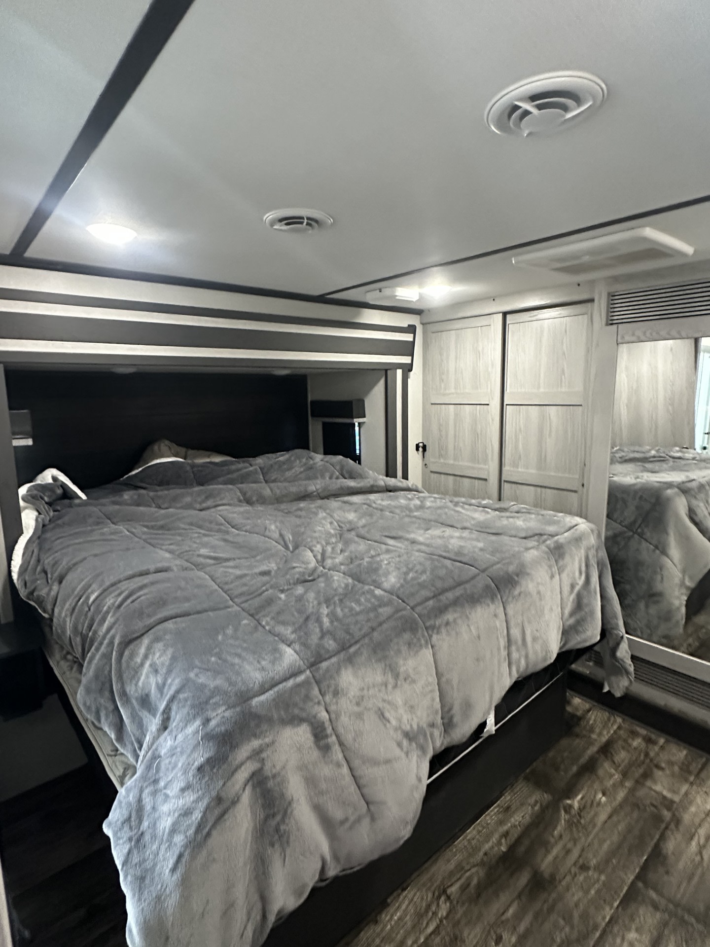 Inside a cozy **rv rental**: A modern bedroom with a large, plush grey bed, light wood closets, and ceiling features.. Keystone RV Fuzion Toy Hauler 2022