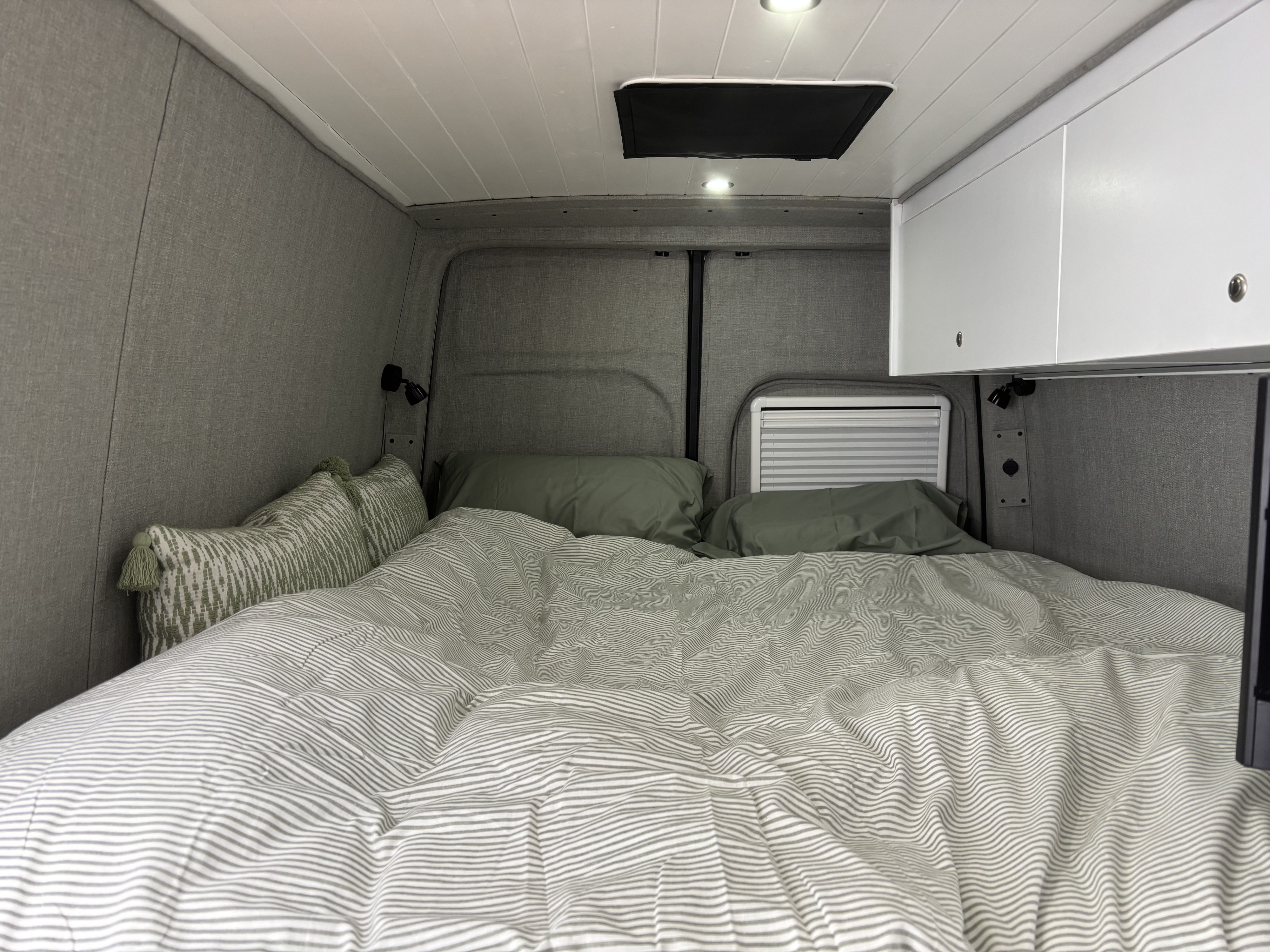 Cozy camper van bedroom setup for your next RV rental adventure. Features a comfy bed, overhead storage & reading lights.. Mercedes-Benz Sprinter 2023