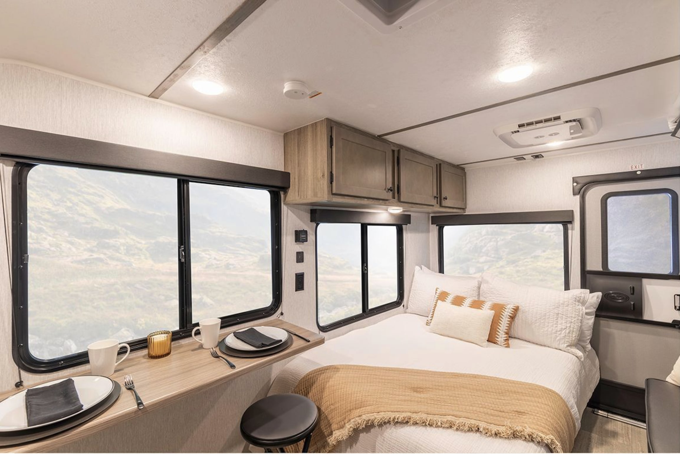 Spacious rv rental interior: bedroom with bed, panoramic windows, dining counter & overhead storage. Ideal for travel comfort.. Wayfinder Go Lite Cloudbreaker 2026