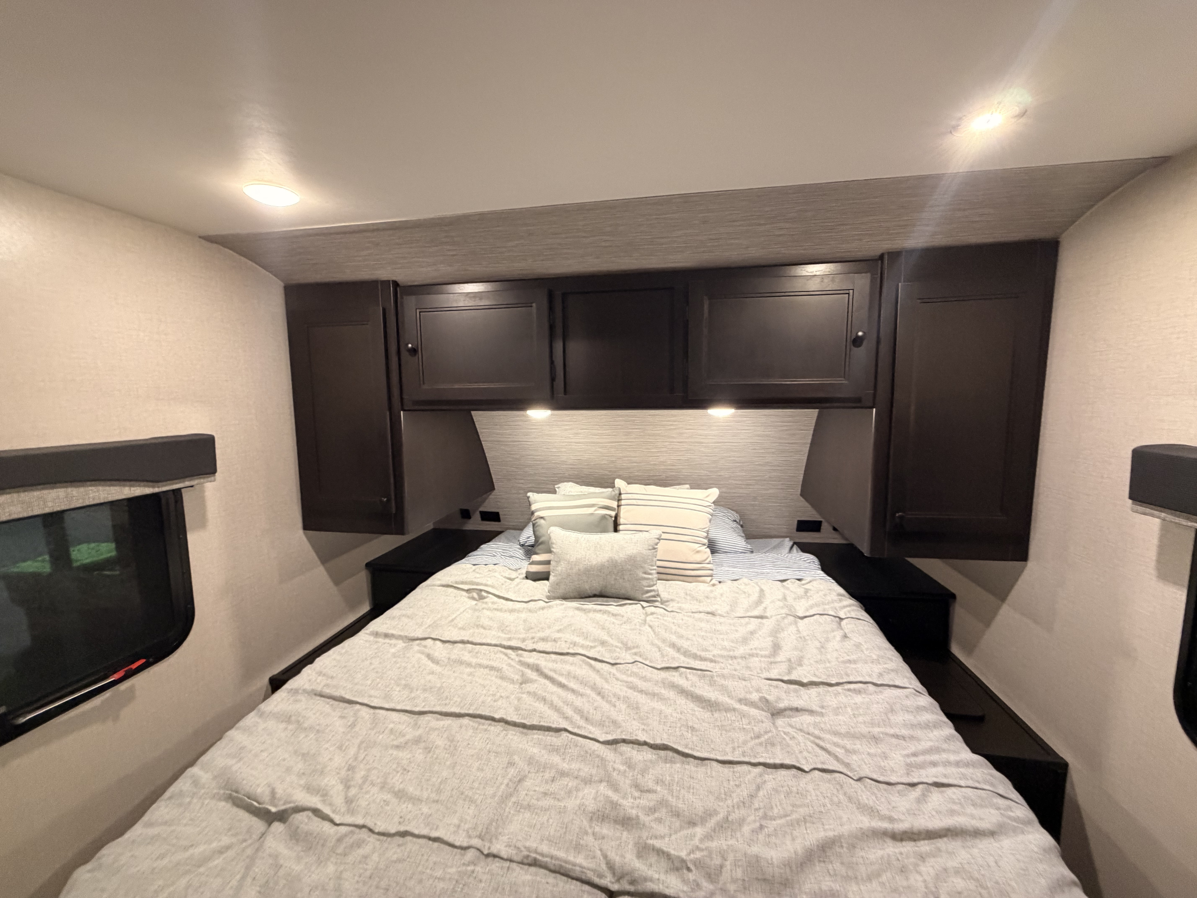 Cozy RV rental bedroom featuring a comfy bed with light bedding, overhead storage cabinets, and ambient lighting, perfect for your travels.. Starcraft Super Lite 2022