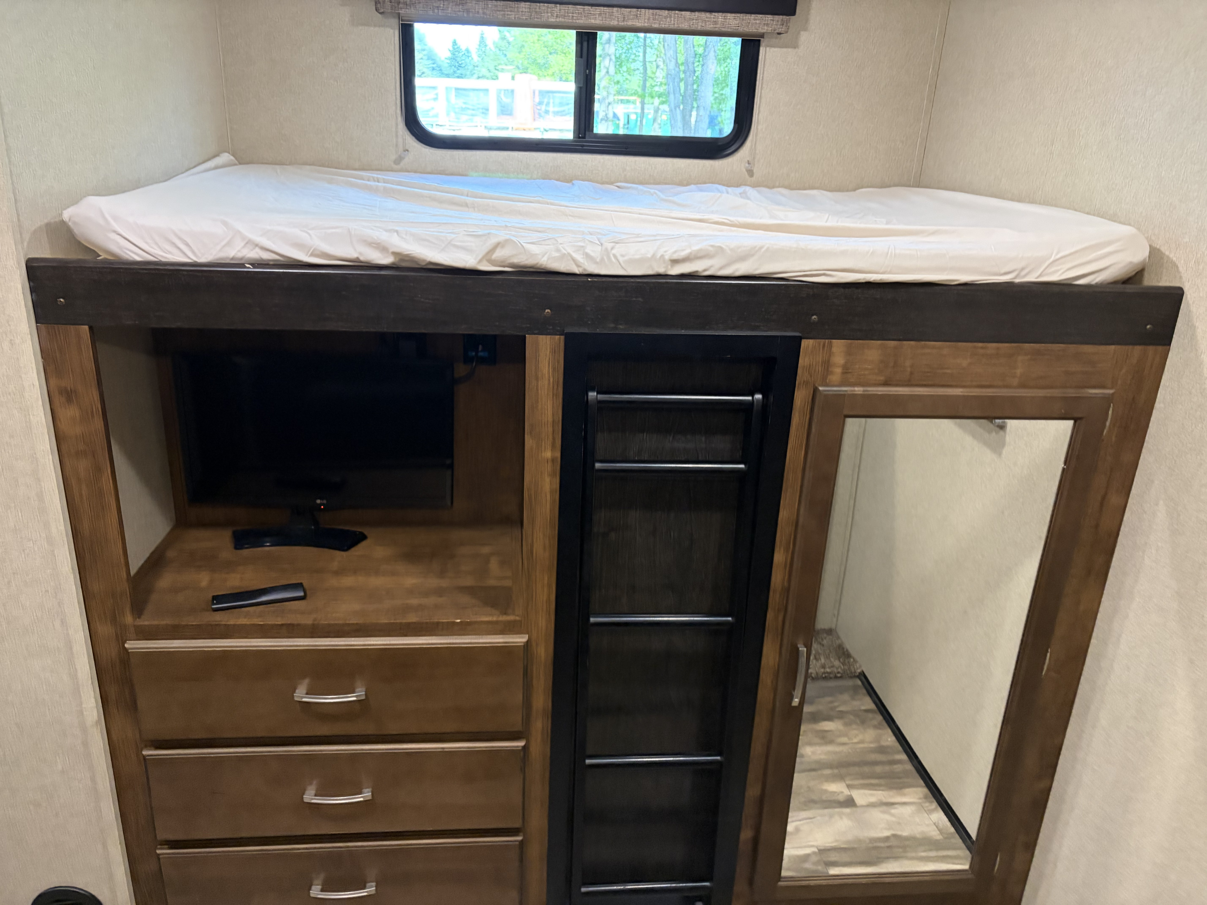 Cozy RV rental bunk bed with window, TV, storage drawers, access ladder, and full-length mirror.. Grand Design Reflection 2020