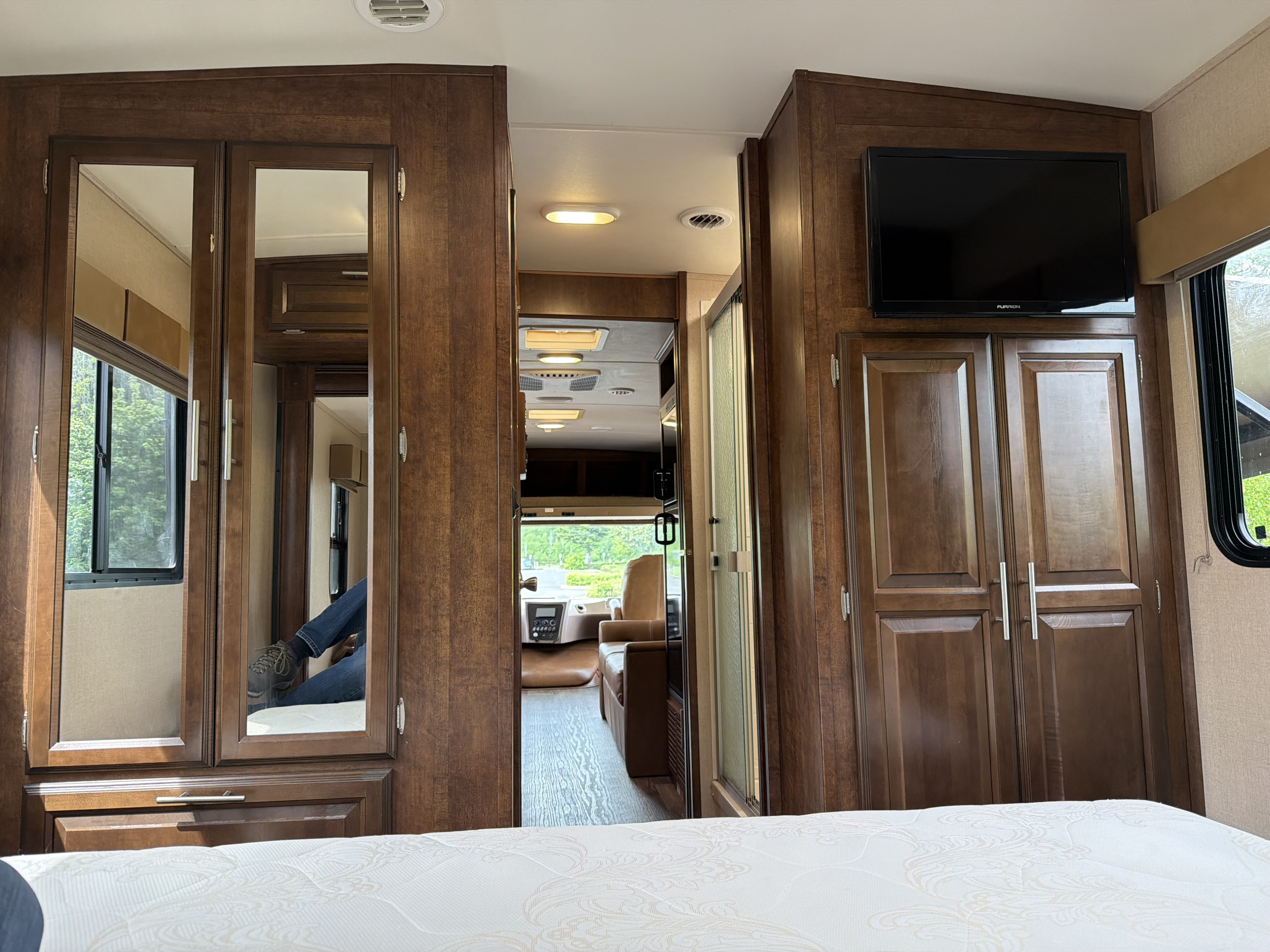 Inside a spacious RV rental, viewing the bedroom with mirrored wardrobe and TV, leading to the living space and cockpit.. Forest River FR3 2016