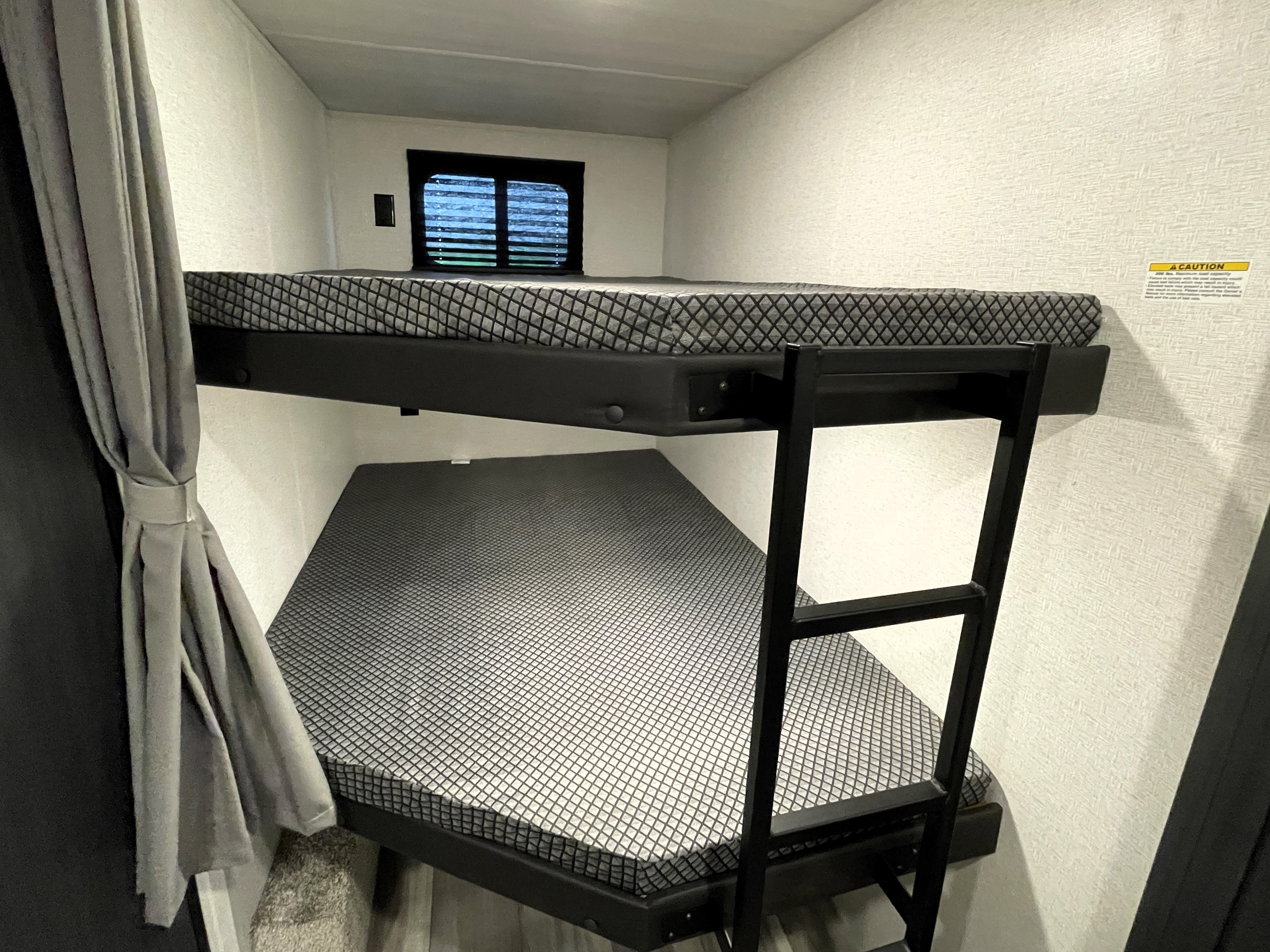 RV rental sleeping area: compact bunk beds with patterned mattresses, a ladder, and a window for family camping comfort.. Keystone RV Hideout Sport 2024