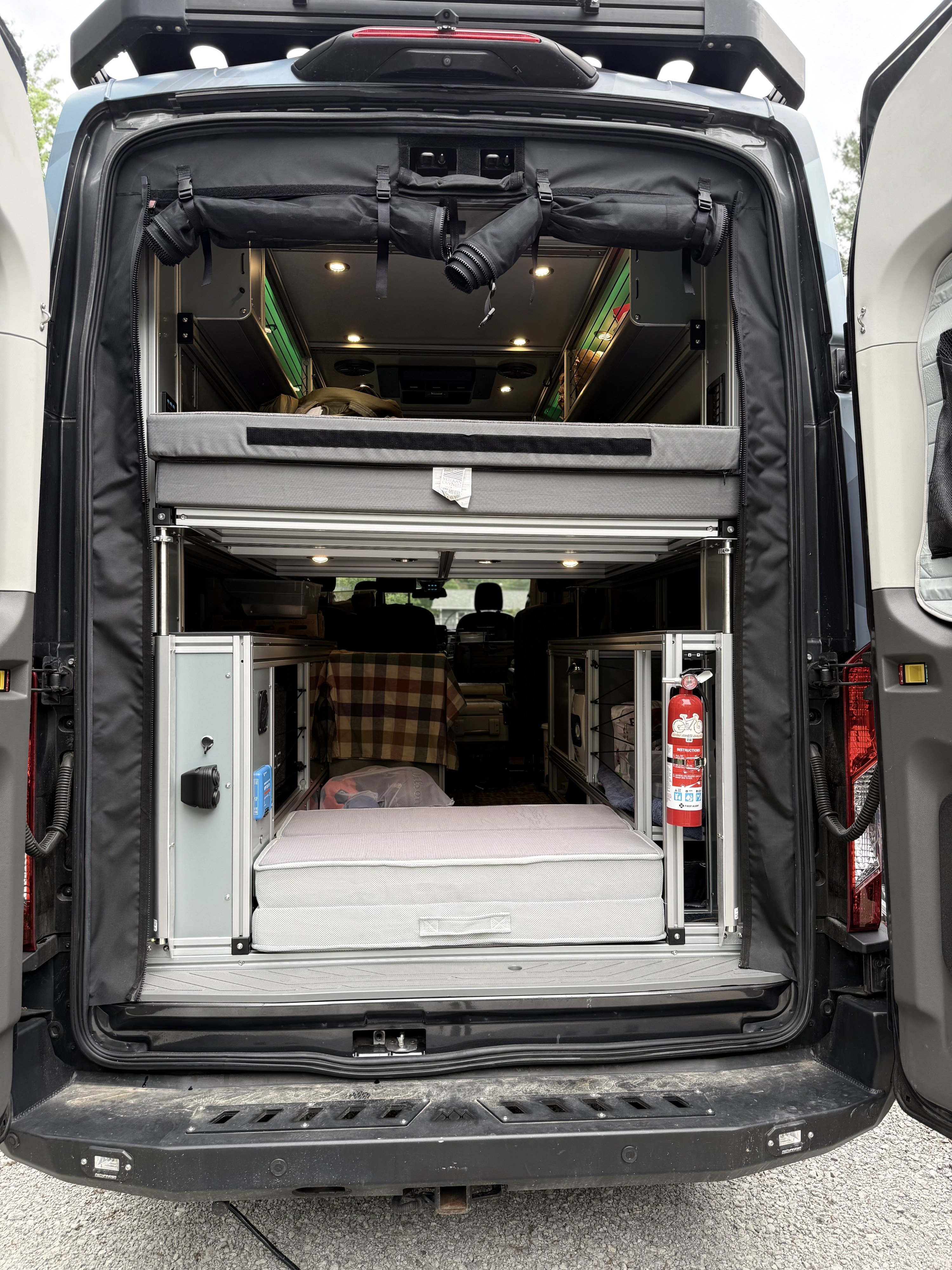 Rear view inside a custom camper van, highlighting its multi-level bed and storage setup for your next rv rental adventure.. Ford Transit 2020