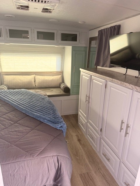 RV rental bedroom with a cozy bed, window seat, ample storage, and TV, offering a comfortable space.. Forest River Flagstaff Super Lite 2021