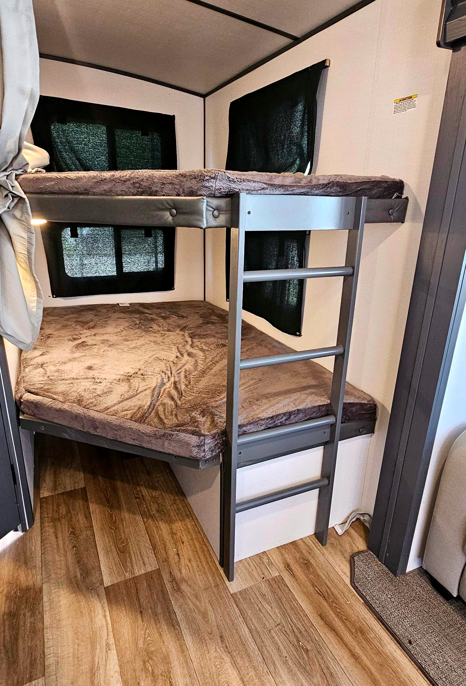 RV rental interior showing bunk beds with ladder, privacy shades on windows, & wood floor. Ideal for camper travel.. Keystone RV Bullet Ultra Lite 2023