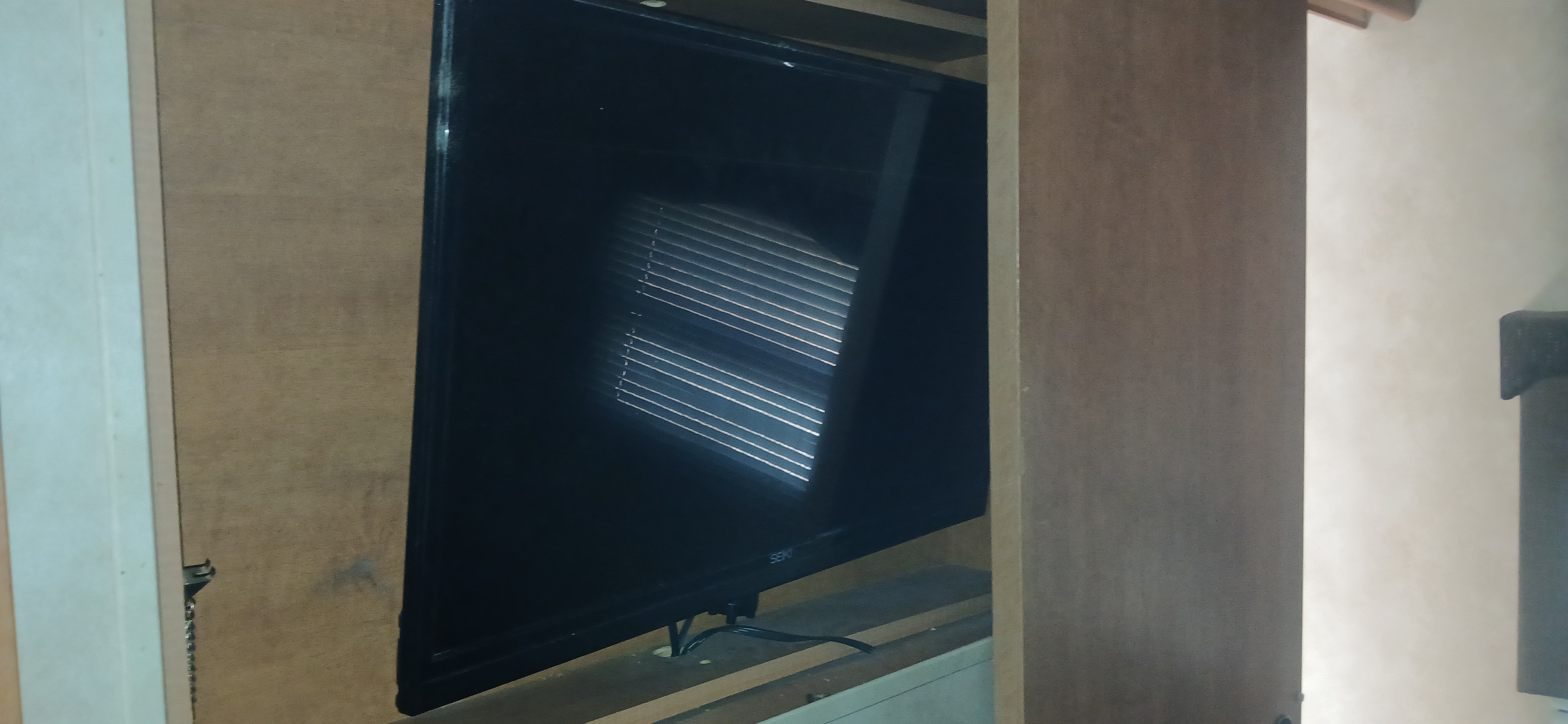 TV in an **rv rental**: A black screen reflects window blinds, nestled in a wooden cabinet, with wires below.. Palomino Puma 2013