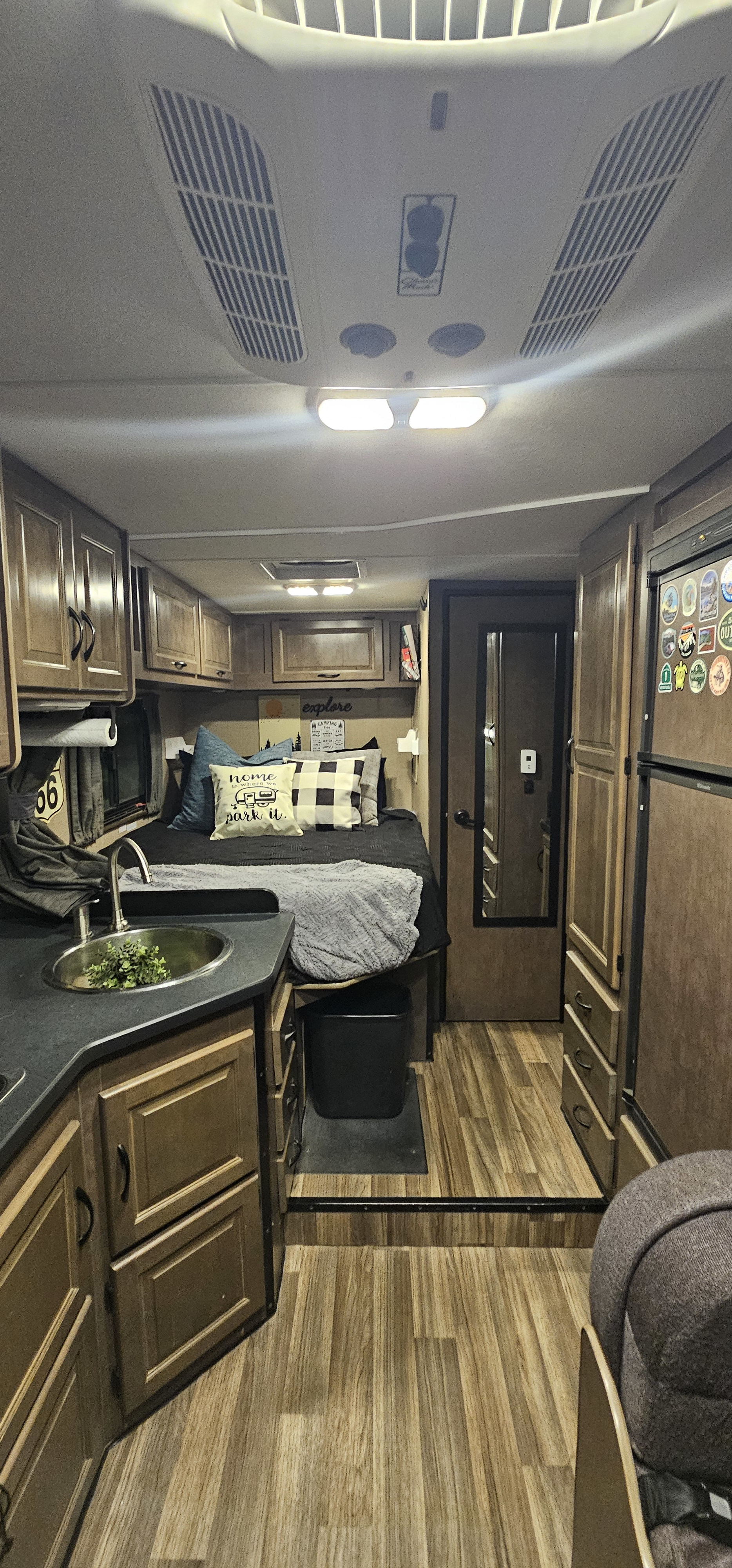 Inside a modern rv rental: kitchen sink, cozy bed, and warm wooden cabinets create a compact, inviting space.. Thor Majestic 2017