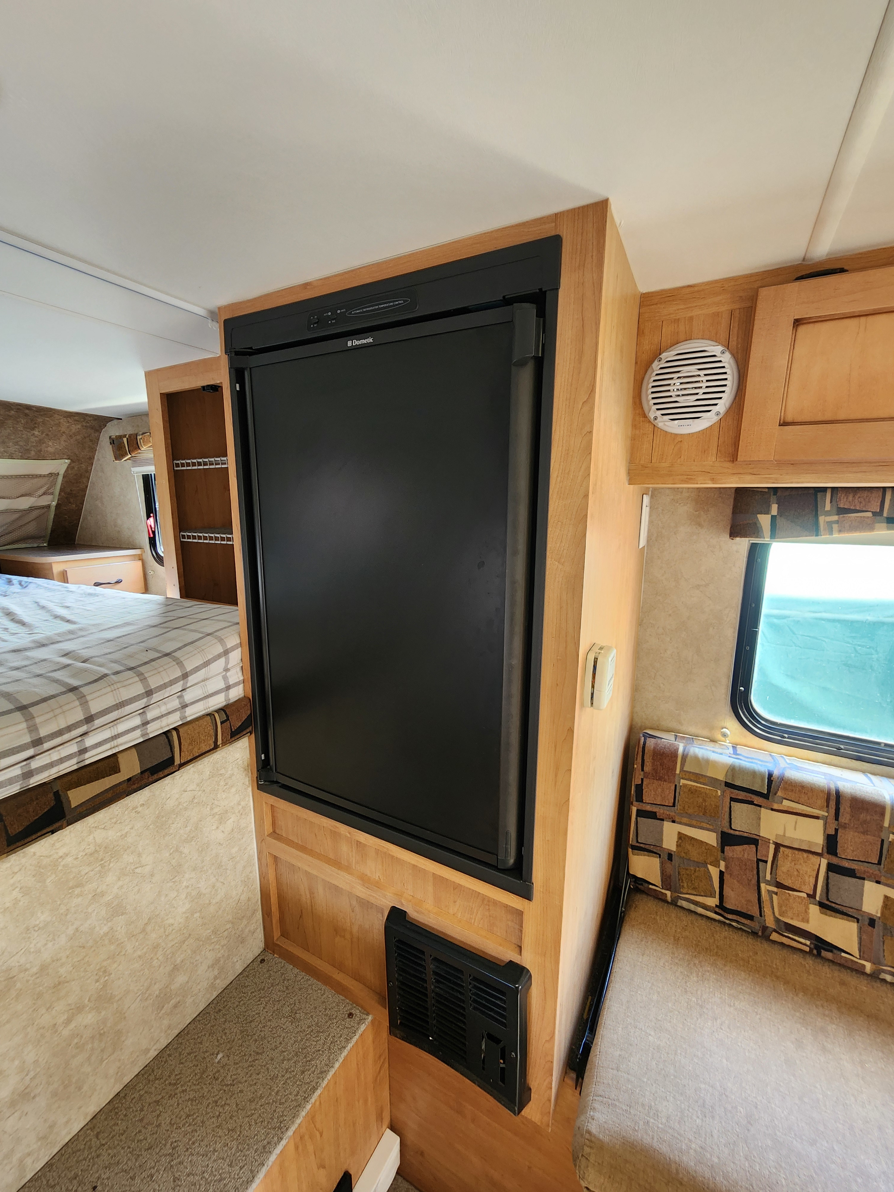 RV rental interior featuring a Dometic refrigerator, a sleeping area with plaid bedding, and a dinette by a window.. Ford Ford F150 2018
