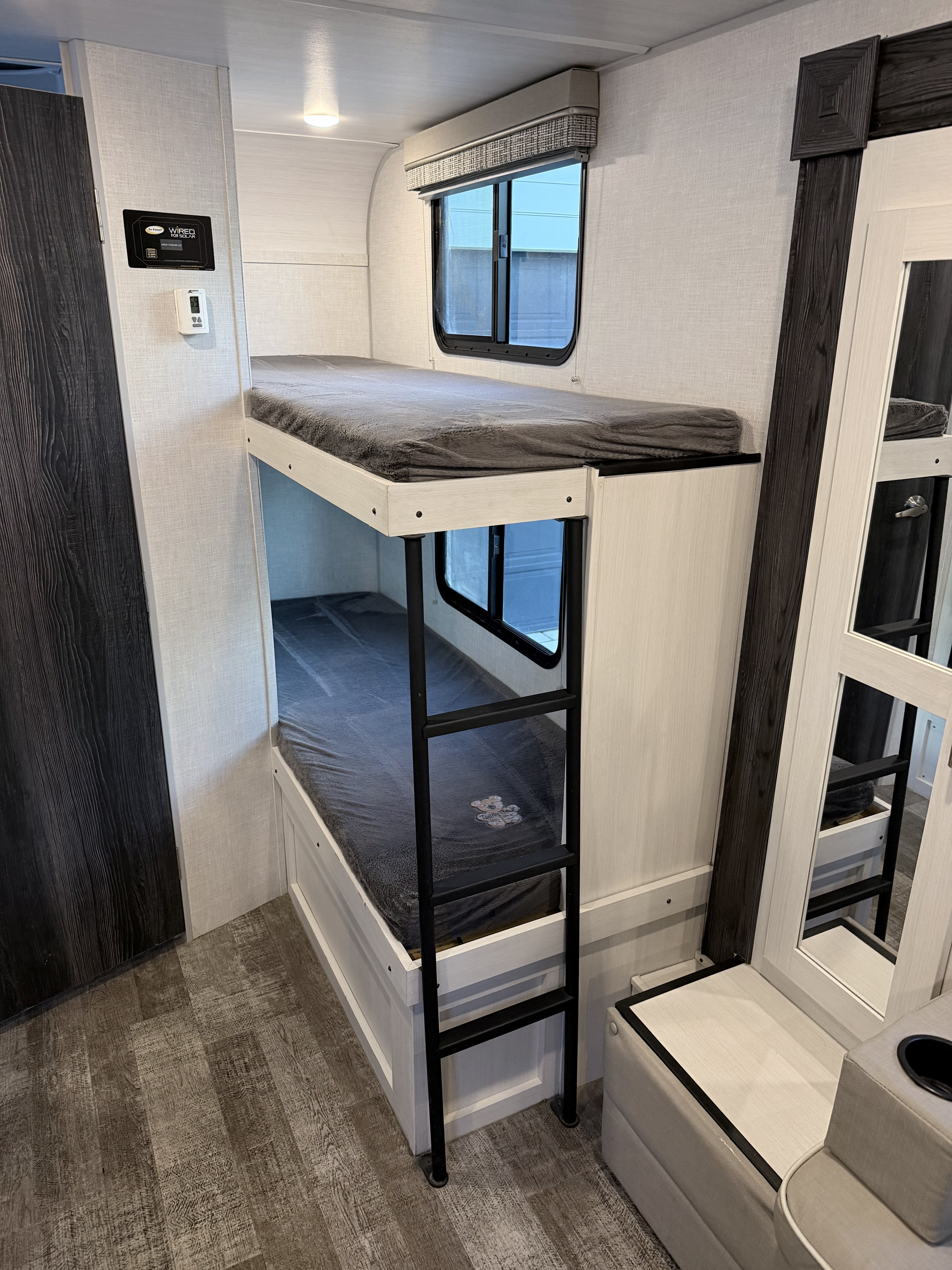 RV rental interior: two bunk beds with soft blankets, a ladder, and windows, offering compact sleeping space for travelers.. Forest River R-Pod 2022
