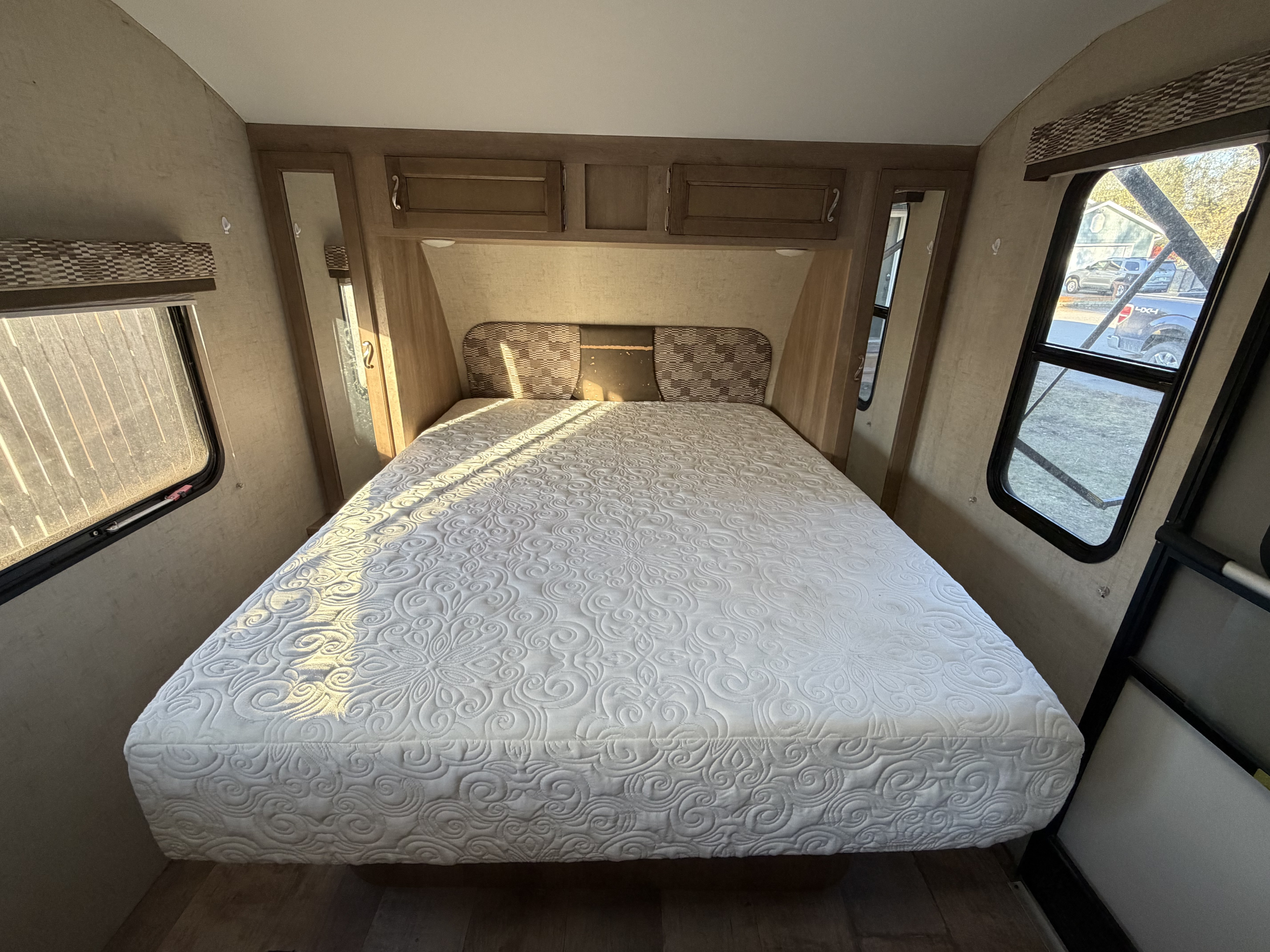 Bright rv rental bedroom: A large bed with a white quilted mattress, overhead cabinets, mirrored wardrobes, and sunny windows.. KZ RV Sportmen Classic 19RB 2016