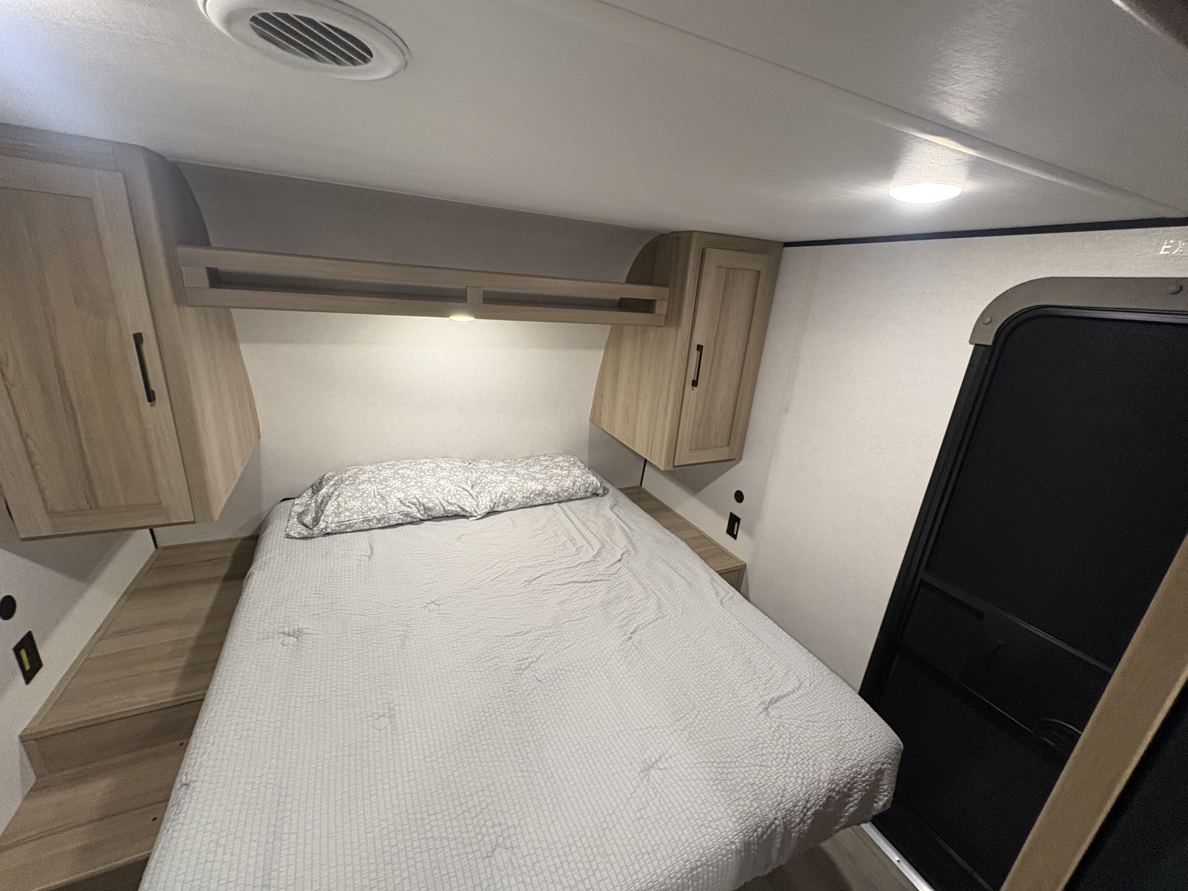 Modern RV rental bedroom featuring a comfortable bed, convenient overhead storage, and integrated lighting.. Keystone RV Other 2026