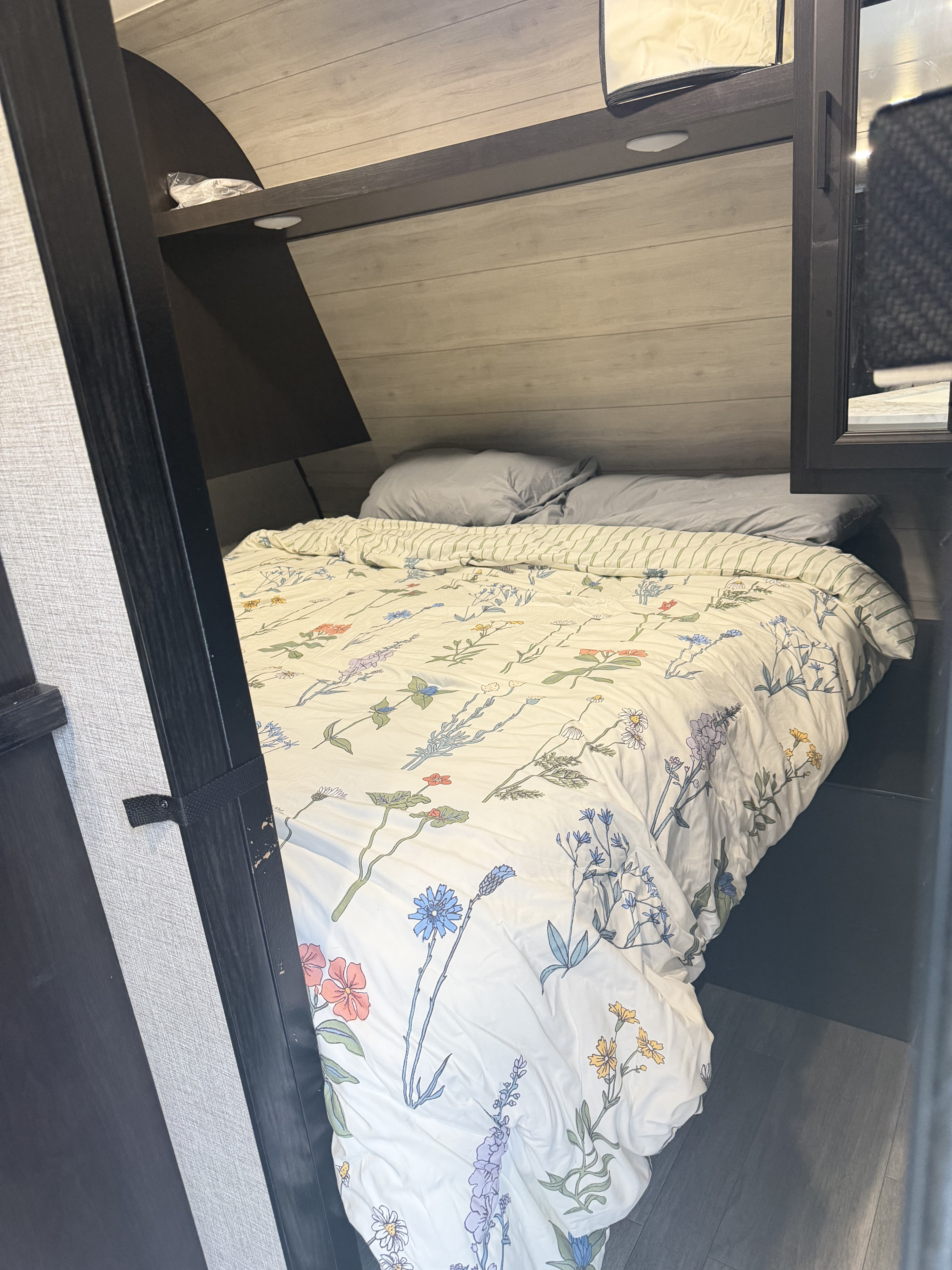 Cozy RV rental bedroom featuring a bed with a floral duvet, grey pillows, and light wood-paneled walls.. Jayco Jay Flight SLX 2022