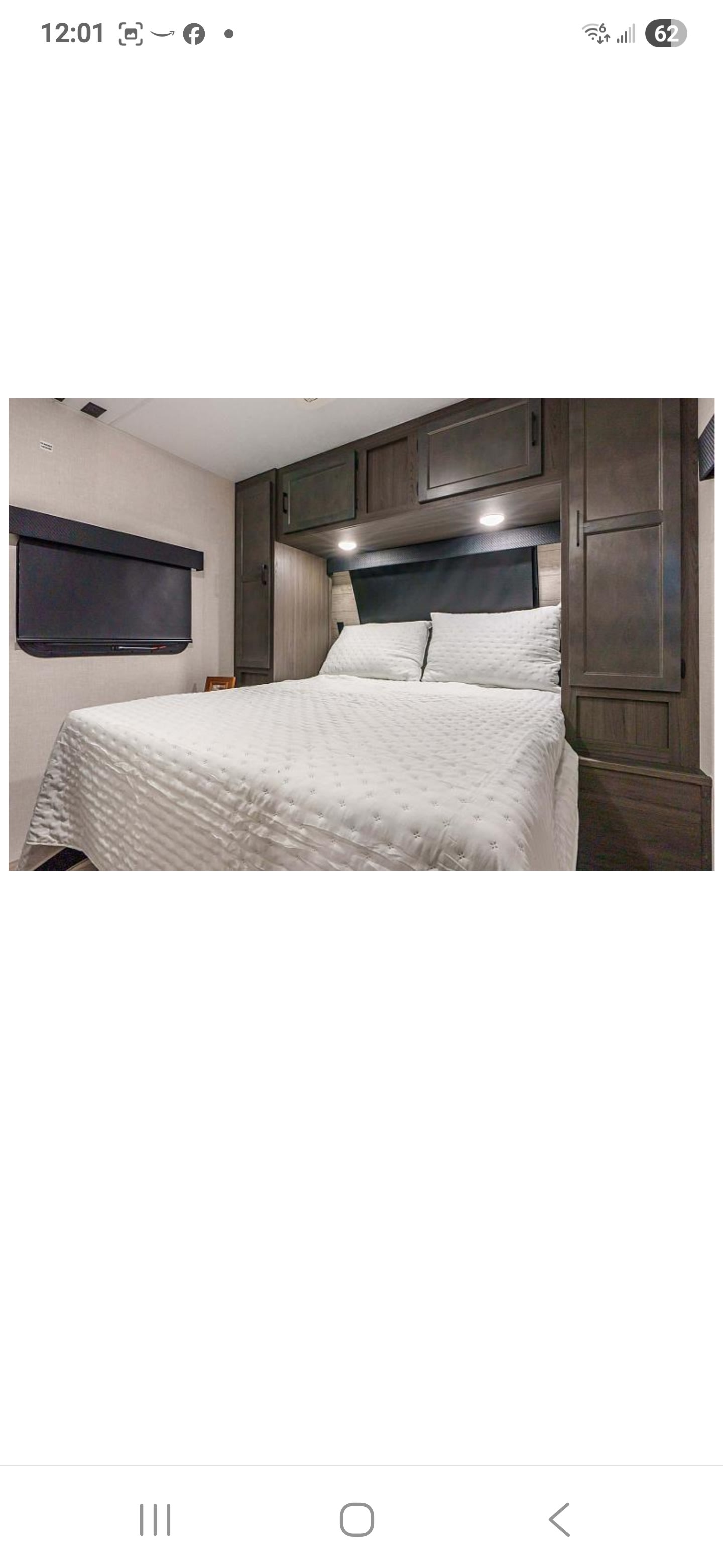 Cozy RV rental bedroom with white bed, dark wood cabinets, & wall-mounted TV, ideal for your travel trailer adventure.. Sporttrek Sporttrek Trailer 2025