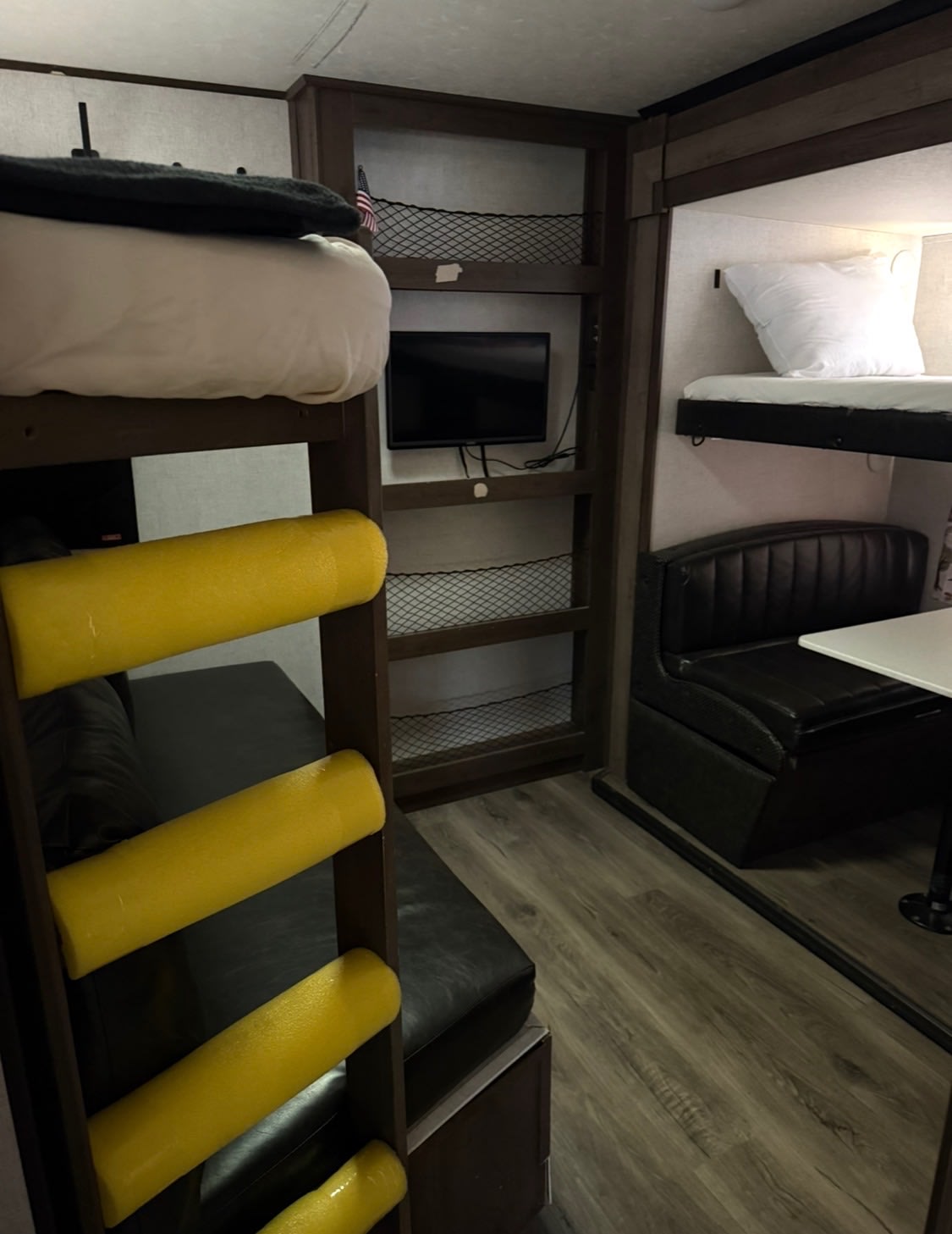 Cozy RV rental interior with bunk beds, yellow ladder padding, a TV, and a booth-style dinette for compact living.. Highland Ridge RV Open Range 2020