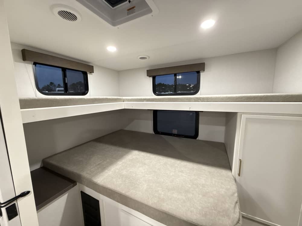 Inside an RV rental: modern bunk beds for comfortable sleeping. Features windows and built-in storage in a bright interior.. Grand Design Transcend 2026