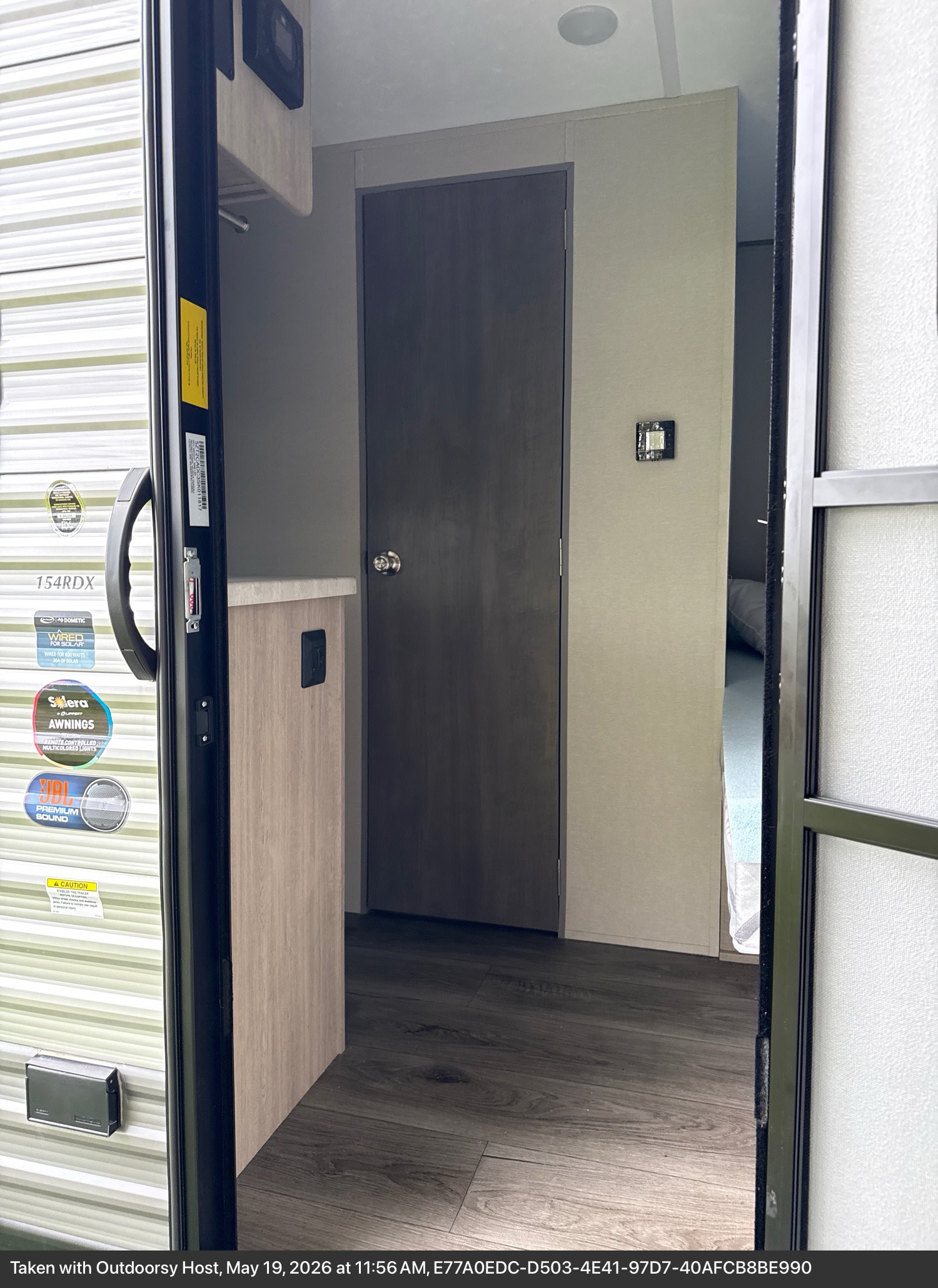 Inside an RV rental, looking past the open door frame. Light walls, wood-look floor, a counter, and an interior door are visible.. Coachmen Catalina 2025