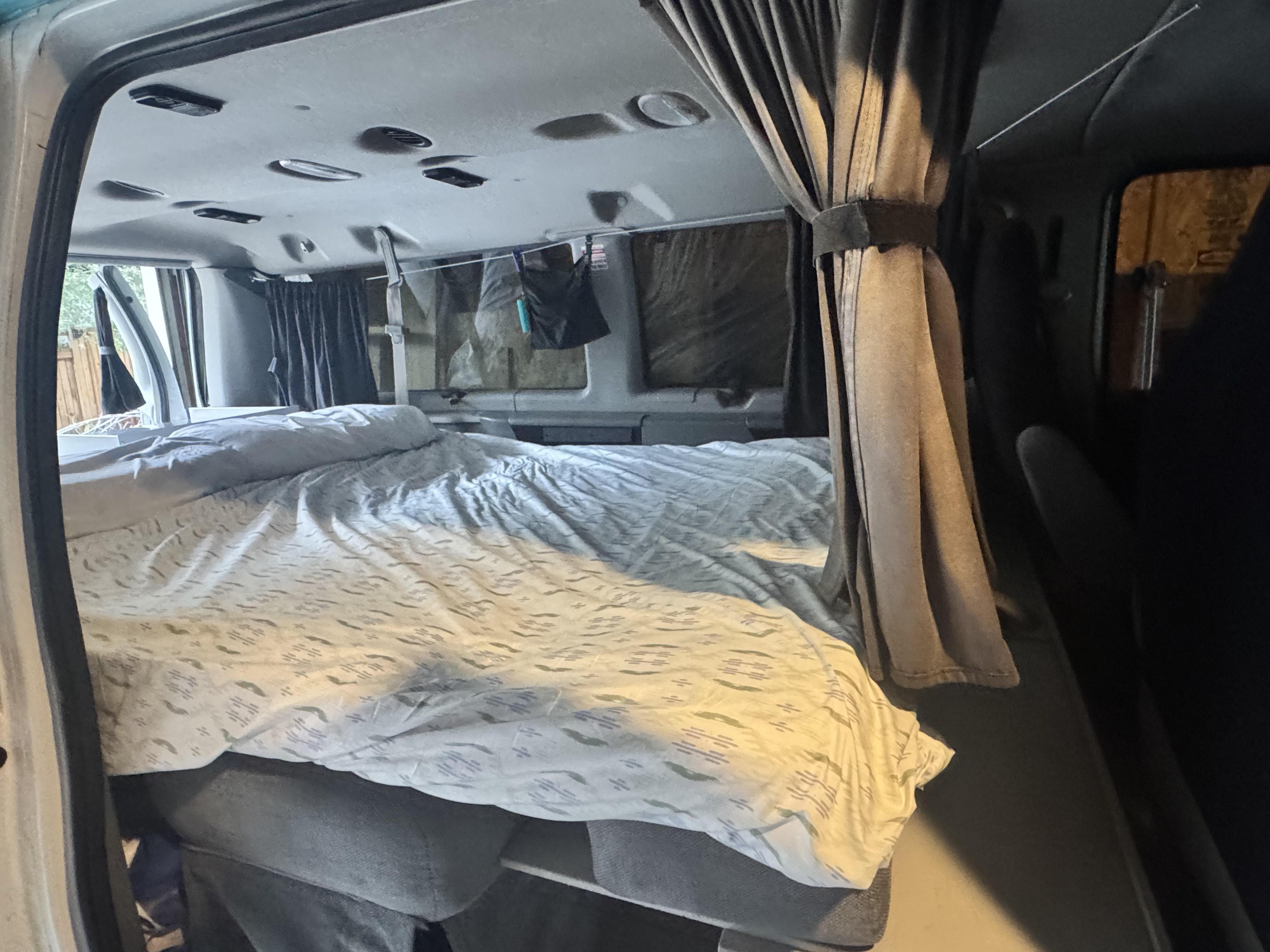 Cozy rv rental interior featuring a comfortable bed with patterned bedding, ready for van life adventures.. Ford Econoline 150 2012