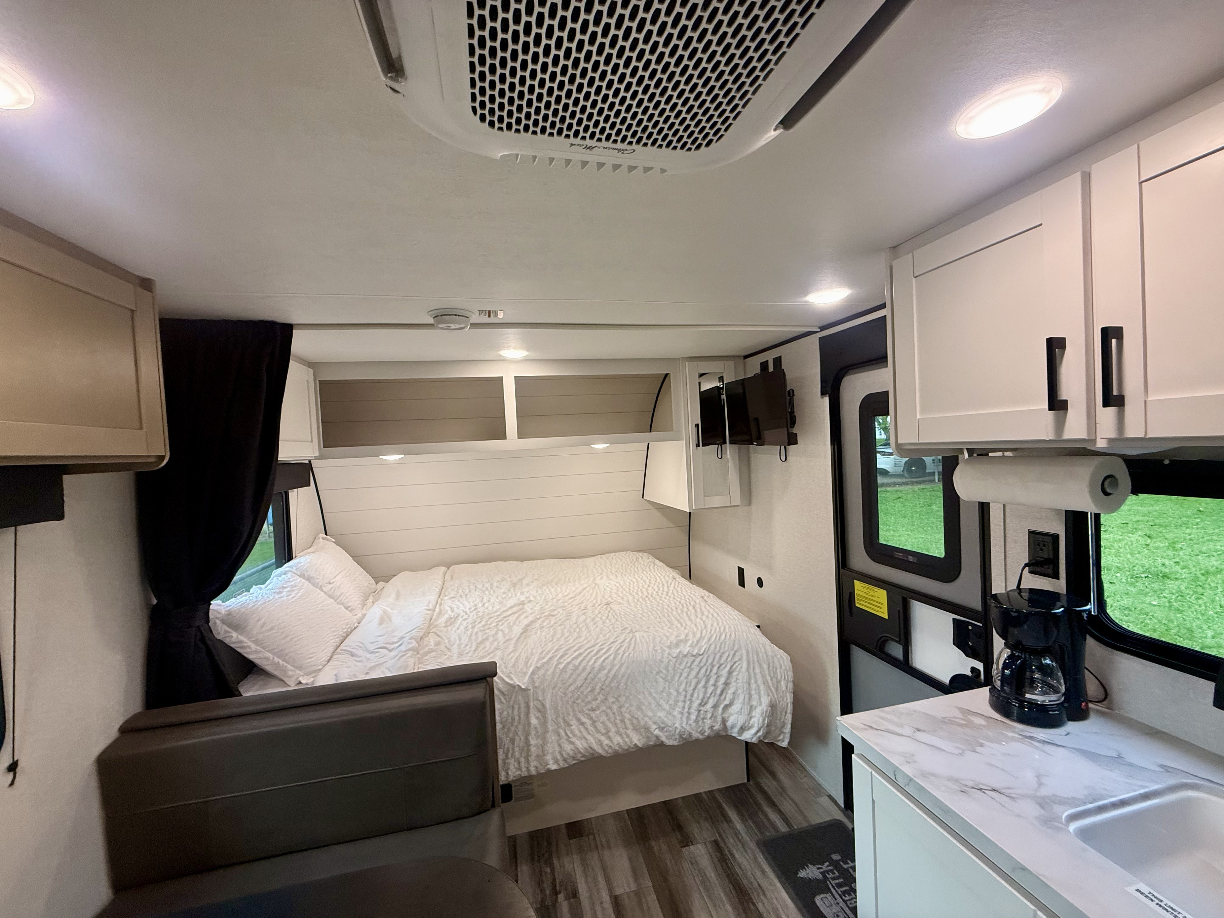 Inside a cozy RV rental: bedroom with a queen bed, integrated kitchen, and overhead AC unit, providing comfort.. Jayco SLX 175BH 2026